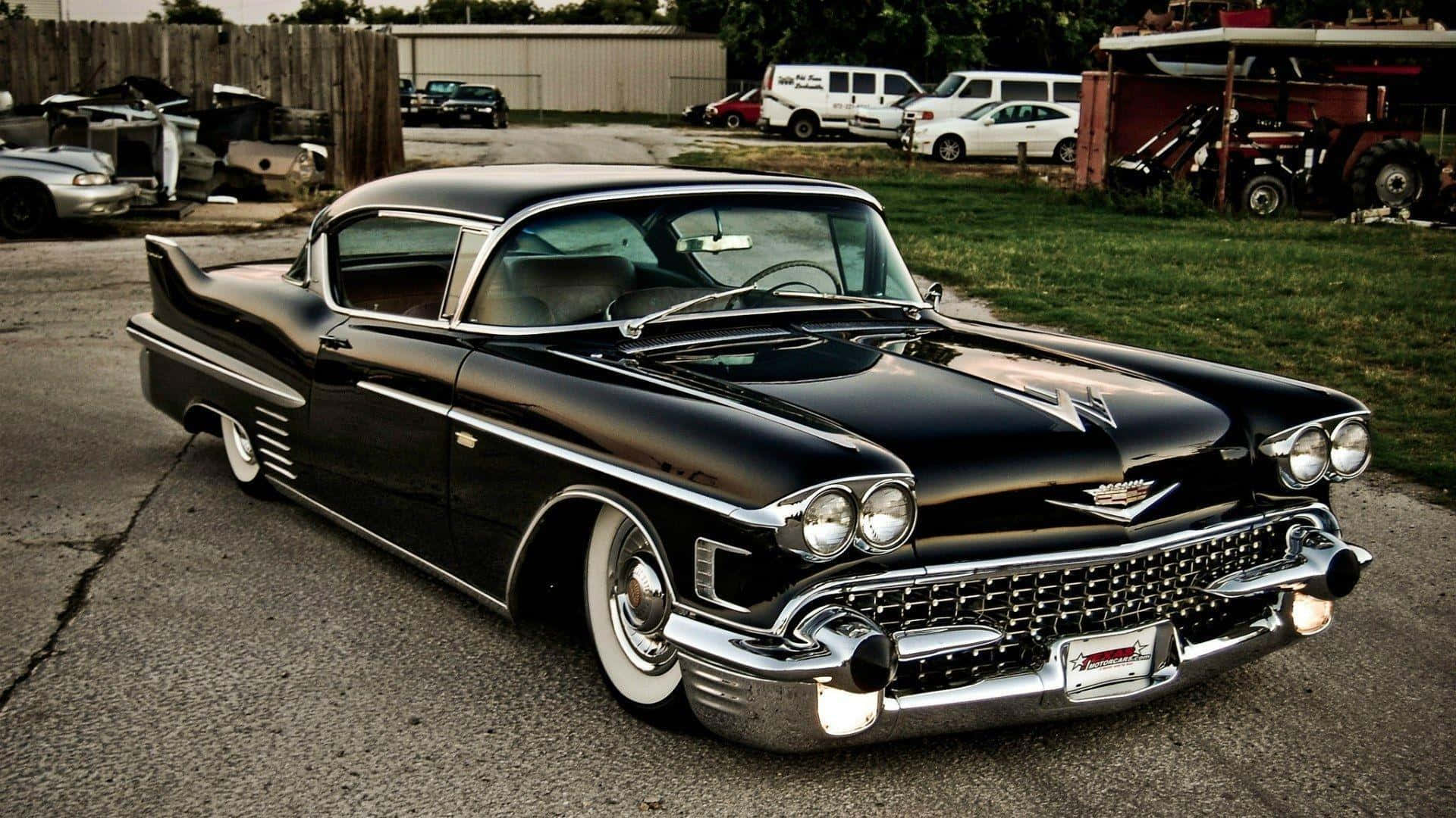 Cadillac 桌布 壁紙 — 一輛閃亮的黑色1959年凱迪拉克，帶有鍍鉻裝飾和白色輪胎，停在鄉村庭院破裂的瀝青上。