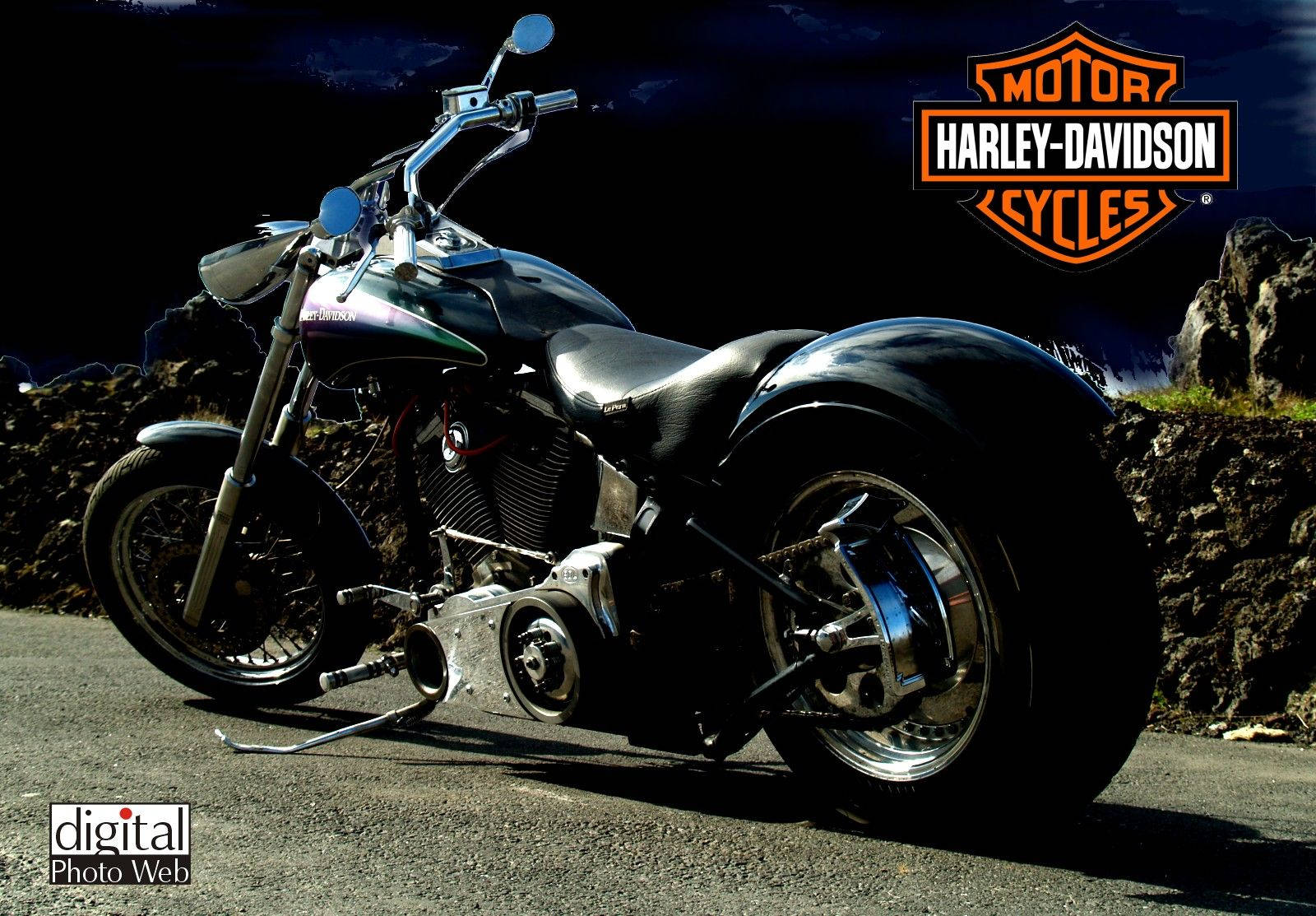 Harley 桌布 壁紙 — 一輛閃亮的黑色Harley-Davidson機車停在柏油路上，背景有崎嶇的岩石和黑暗的天空。