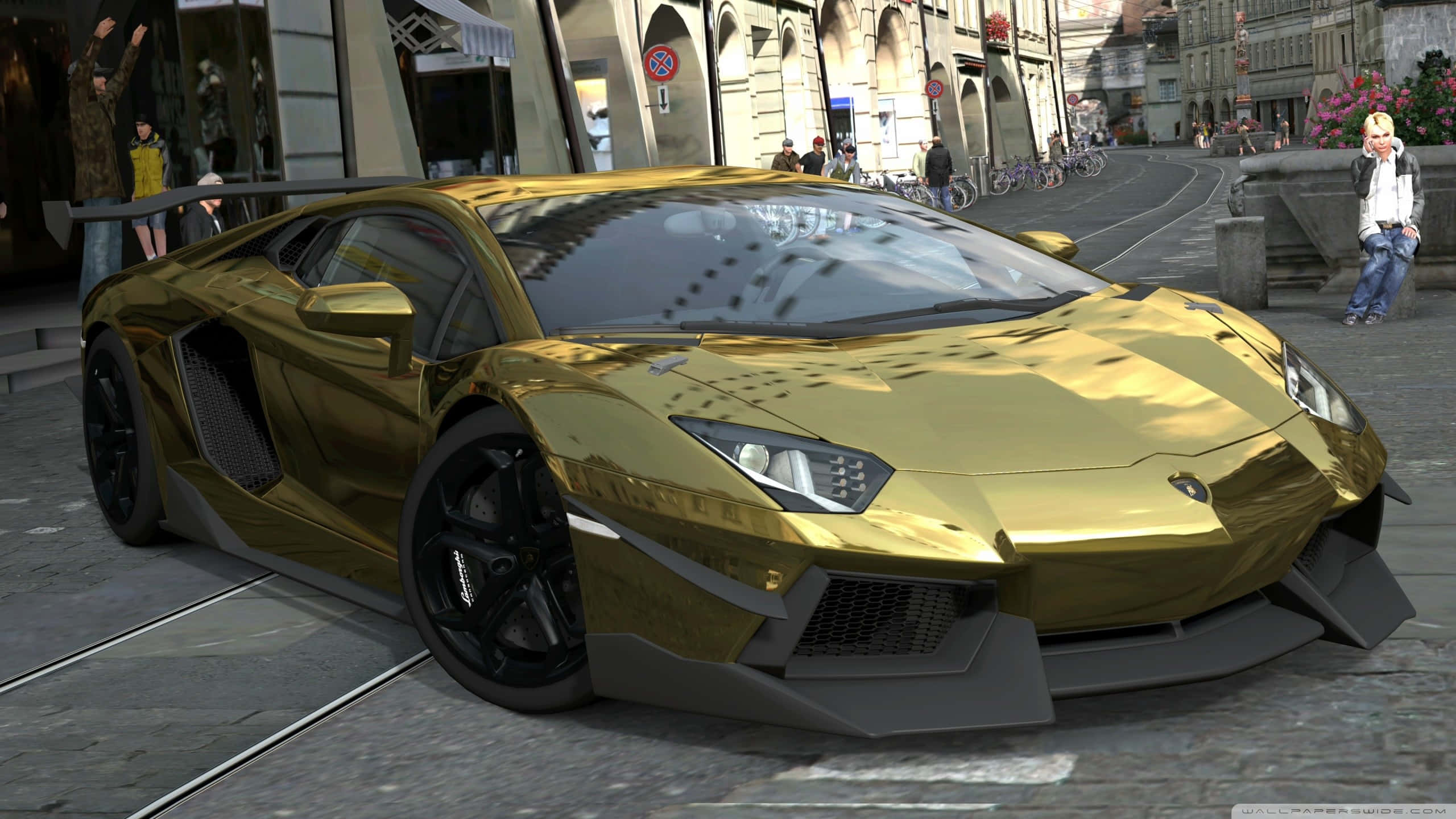 Gold Cars 桌布 壁紙 — 一輛閃閃發光的金色藍寶堅尼Aventador停在歐洲鵝卵石街道上，背景有行人和歷史建築。