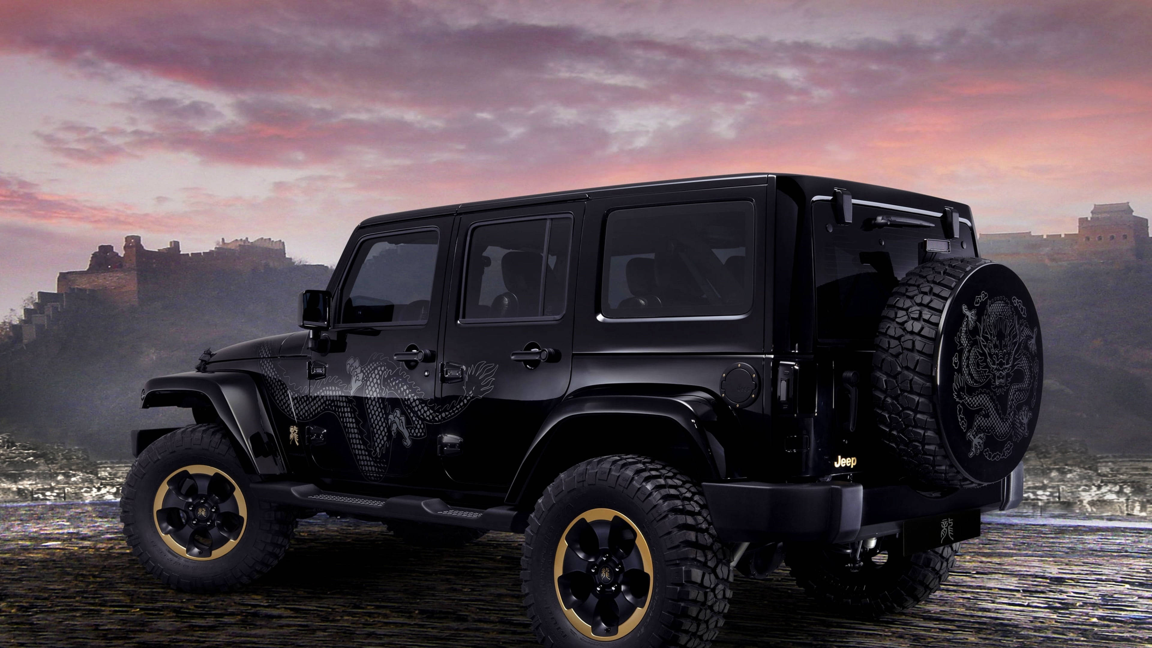 Black Jeep 桌布 壁紙 — 一輛霧面黑色Jeep Wrangler配金色輪圈和龍形貼紙，在日落時分停在霧氣繚繞的長城前的濕岩石上。