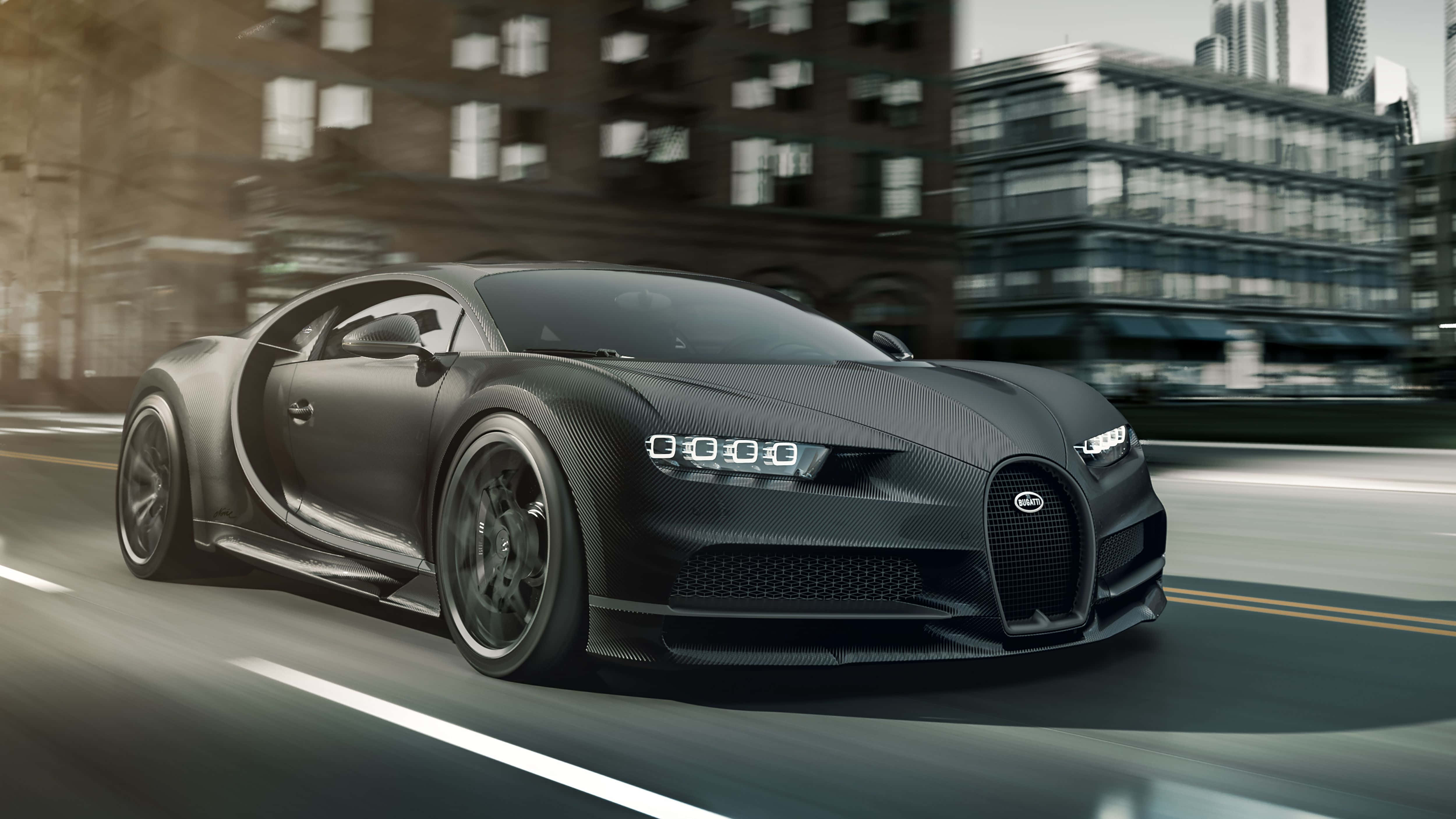 Best Bugatti 桌布 壁紙 — 一輛霧面黑色的Bugatti Chiron在模糊的城市街道上奔馳，背景是現代建築。
