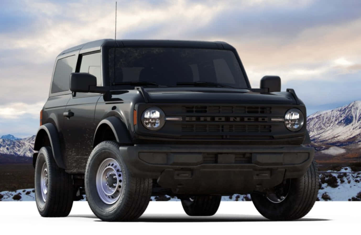 Ford Bronco 桌布 壁紙 — 一輛霧面黑色的福特Bronco在陰天雪景山脈中傲然矗立。