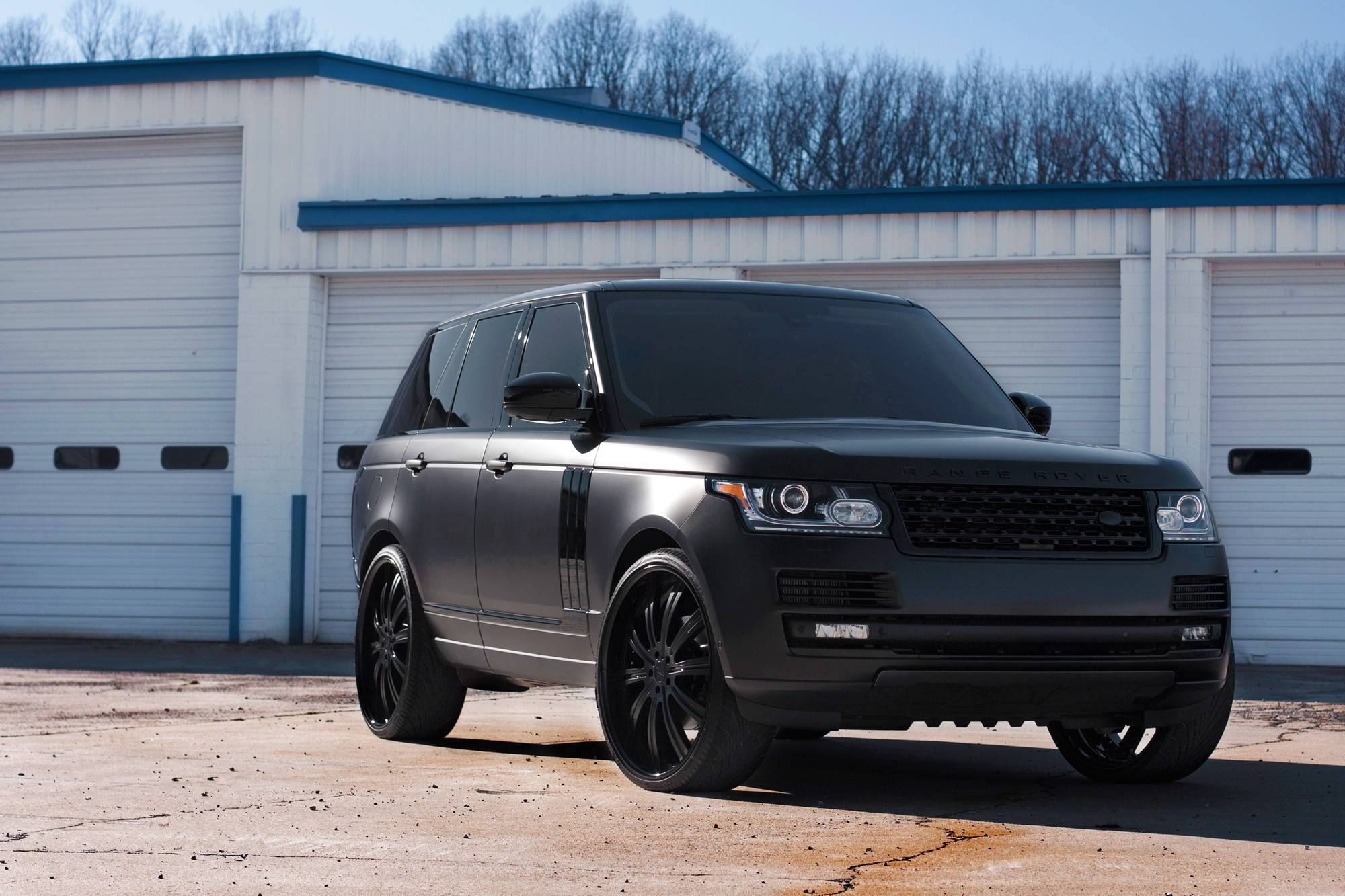 Matte 桌布 壁紙 — 一輛霧黑色Range Rover Sport停放在白色工業建築前，天空清澈湛藍。