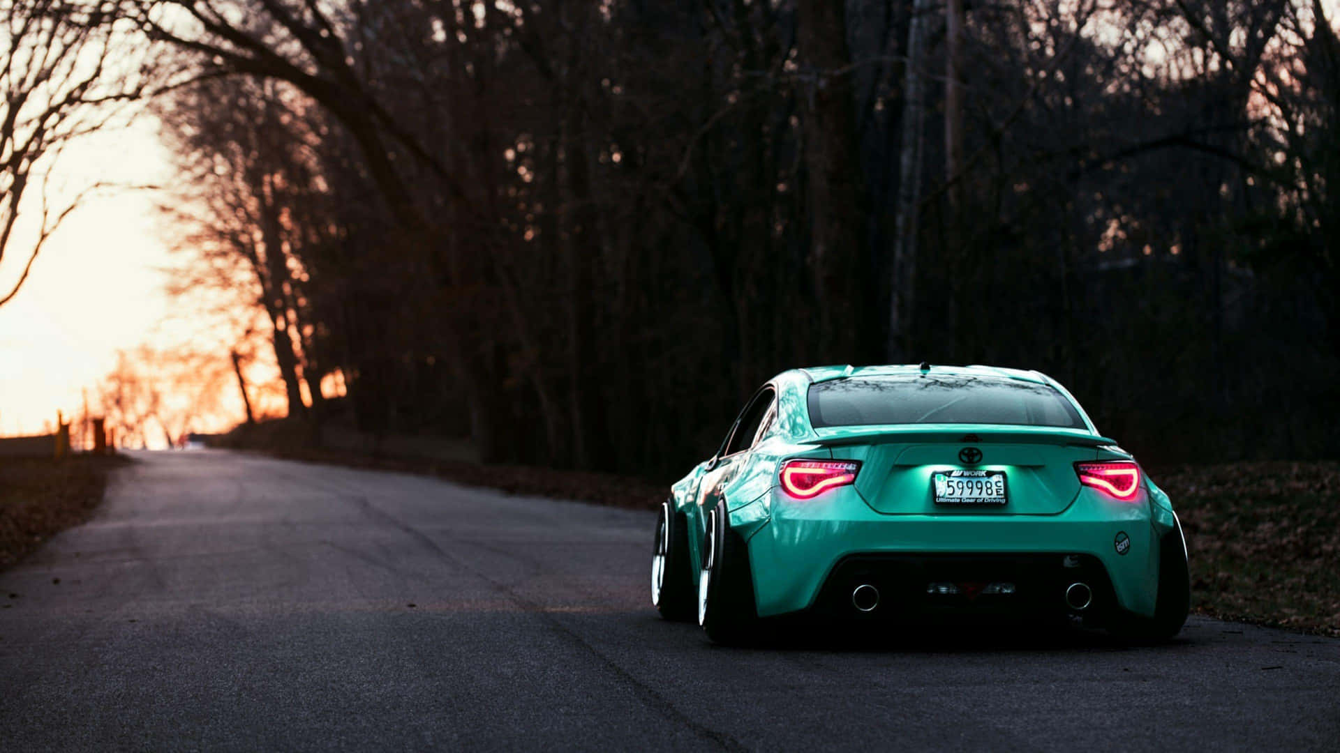 日落時分道路上的青綠色改裝車，尾燈閃爍。 — Toyota Supra Mk4 壁紙