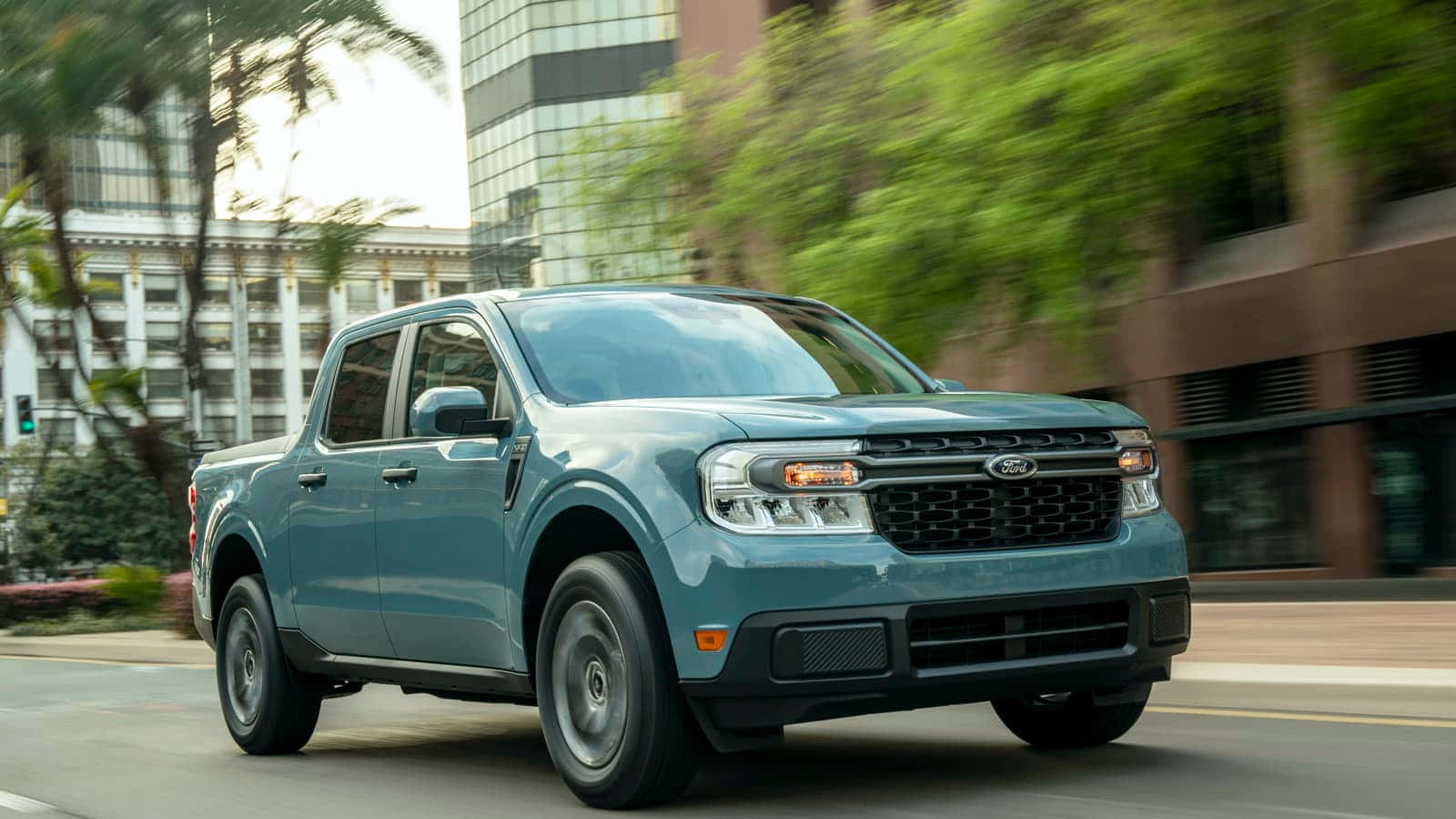 Ford Truck 桌布 壁紙 — 一輛青綠色的福特F-150皮卡在城市的街道上飛馳，背景是模糊的綠化和現代建築。