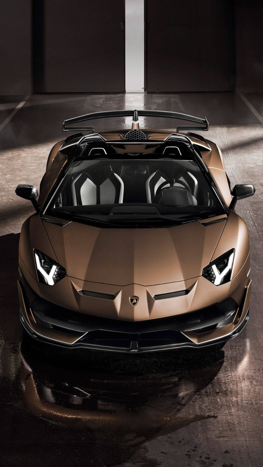 蘭博基尼 桌布 壁紙 — 一輛青銅色藍寶堅尼 Aventador Roadster 在時尚潮濕的車庫中，在戲劇性的燈光下閃閃發光，地板反射出光芒。