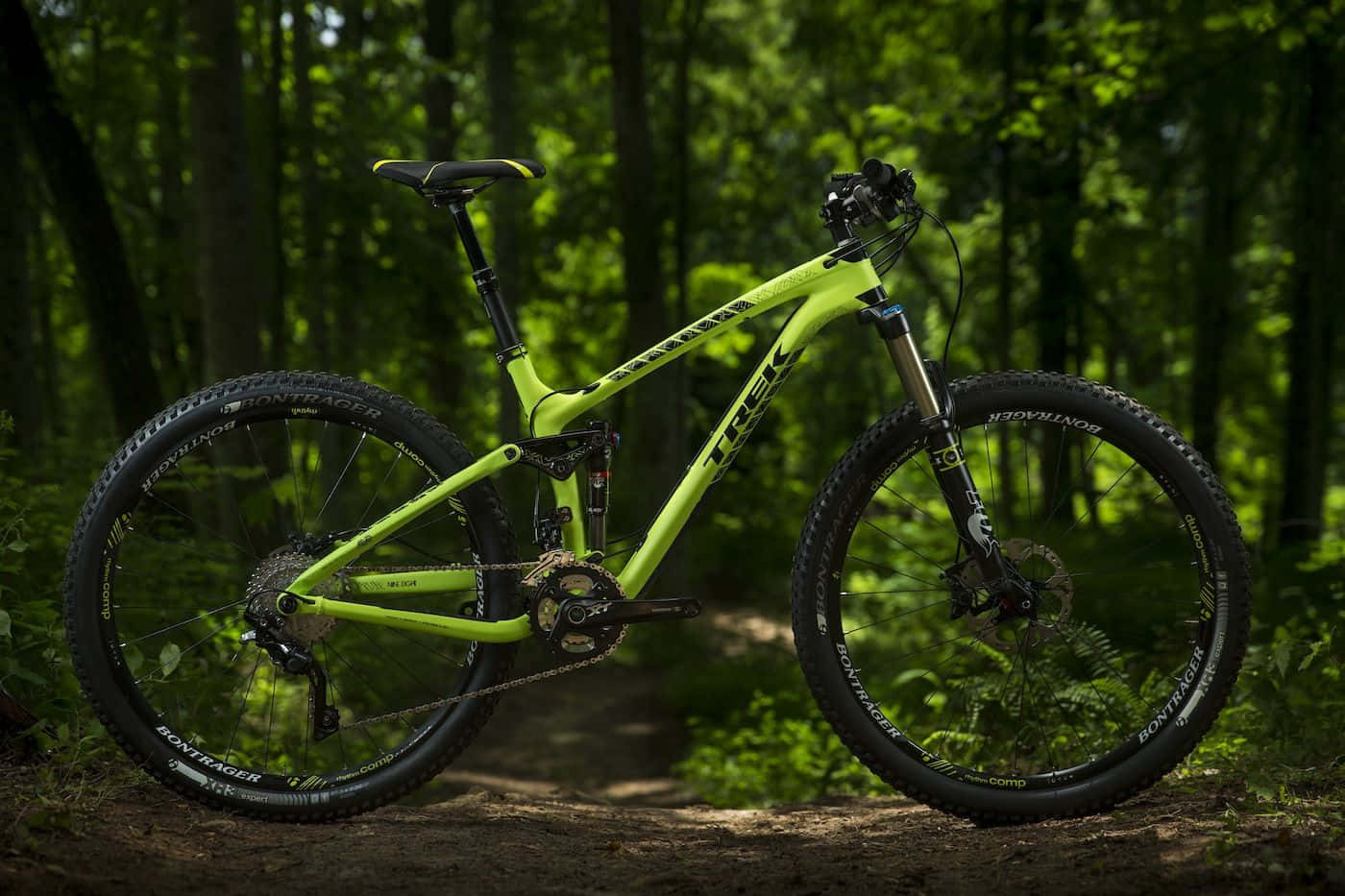 Bikes 桌布 壁紙 — 一輛鮮亮的萊姆綠色Trek登山車佇立在森林小徑上，沐浴在斑駁的陽光中。