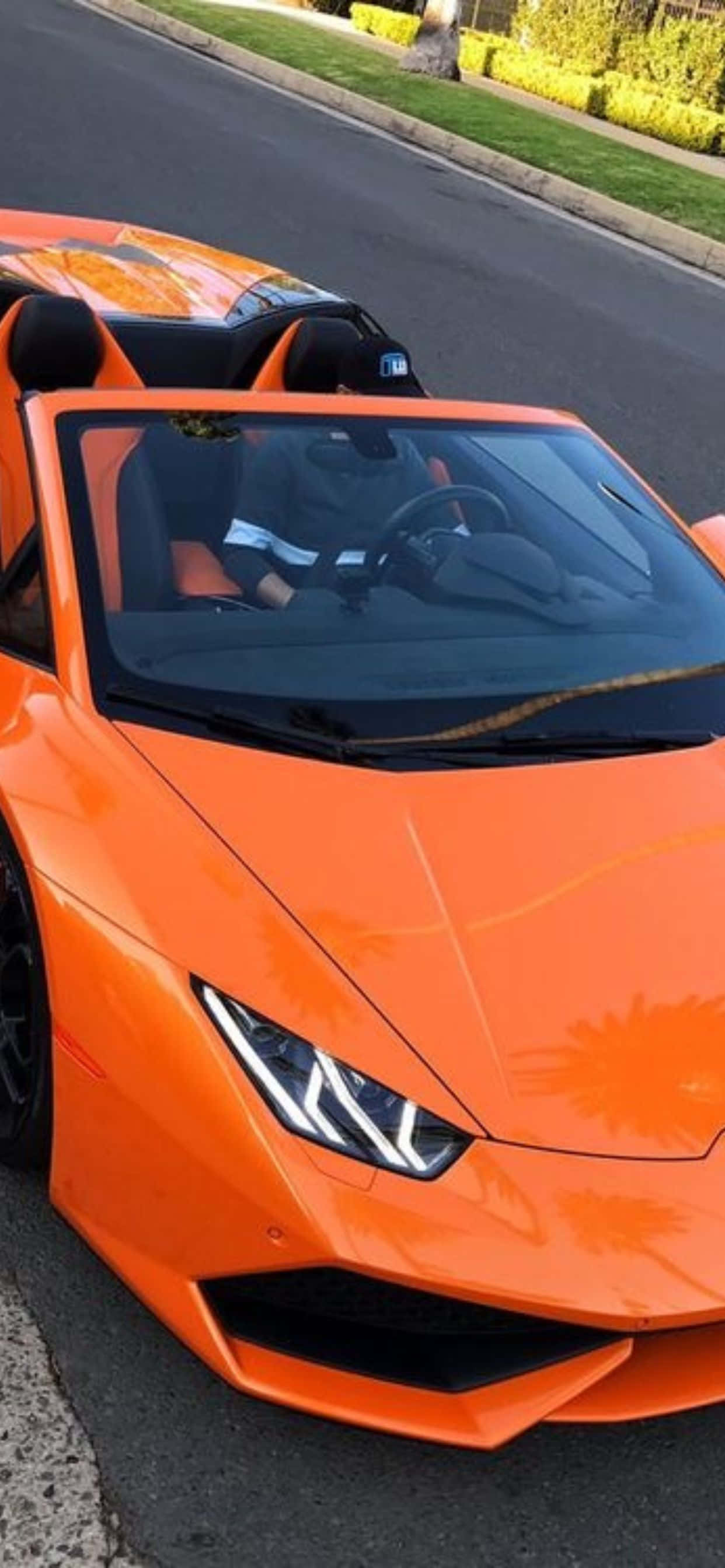 Lamborghini Phone 桌布 壁紙 — 一輛鮮橘色藍寶堅尼Huracán Spyder停放在郊區街道上，駕駛在車內。