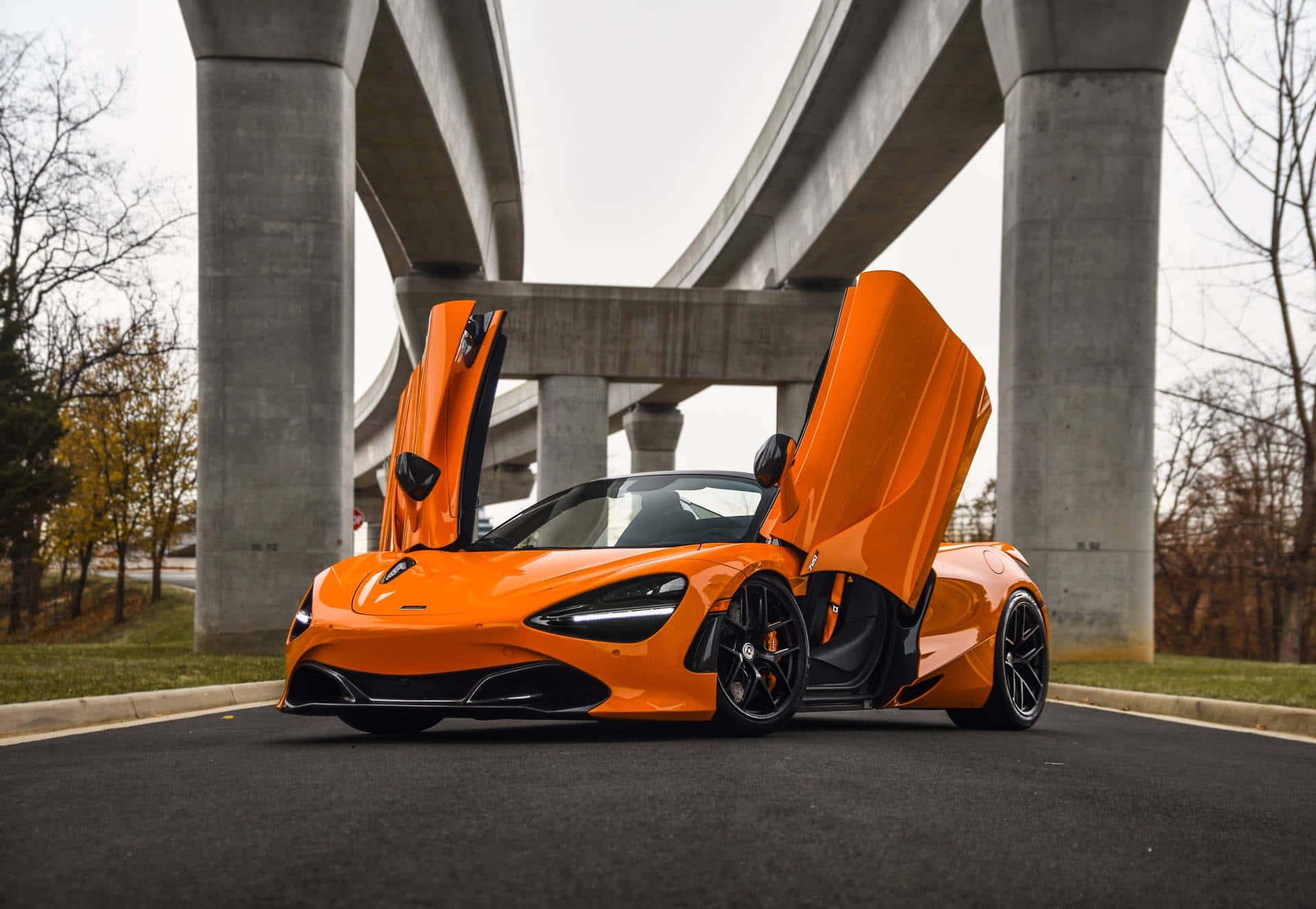 汽車 桌布 壁紙 — 一輛鮮橙色McLaren跑車，鷗翼車門打開，停在柏油路上的混凝土天橋下。