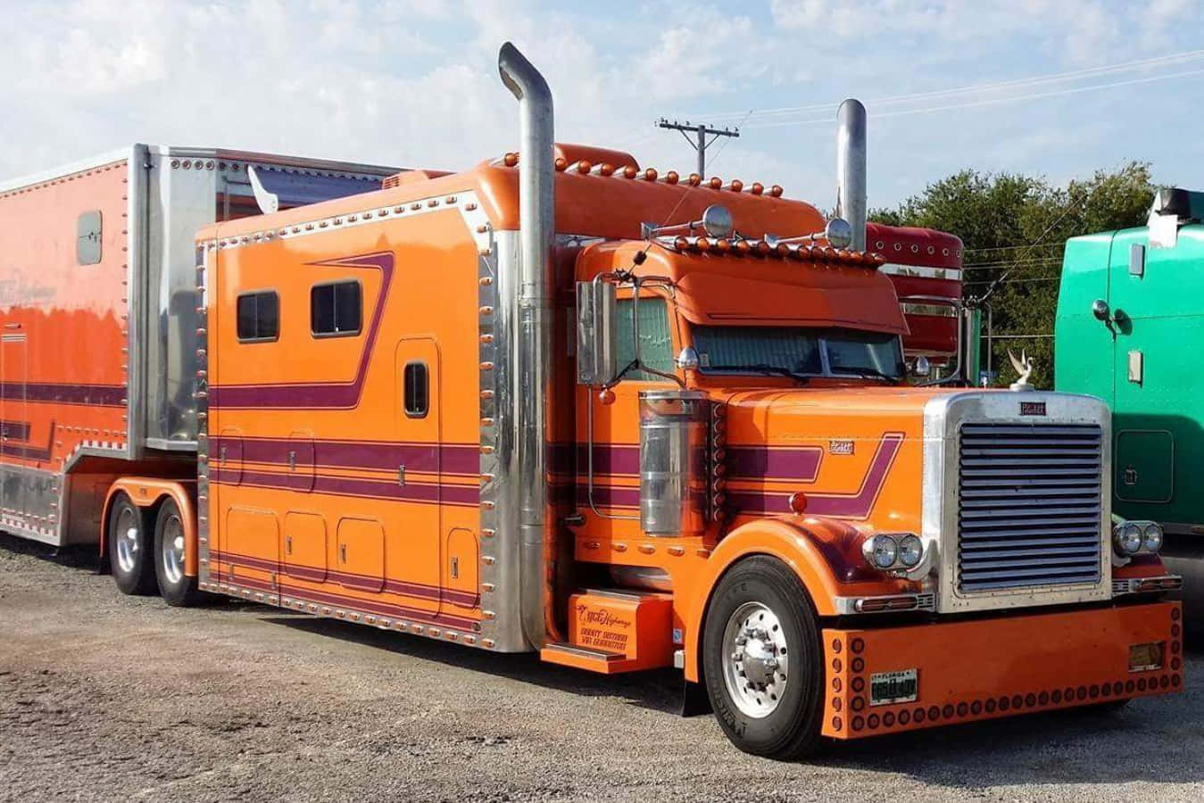 Big Truck 桌布 壁紙 — 一輛鮮橙色定制半掛卡車，帶有紫色條紋和鍍鉻裝飾，停在碎石地上，天空部分多雲。