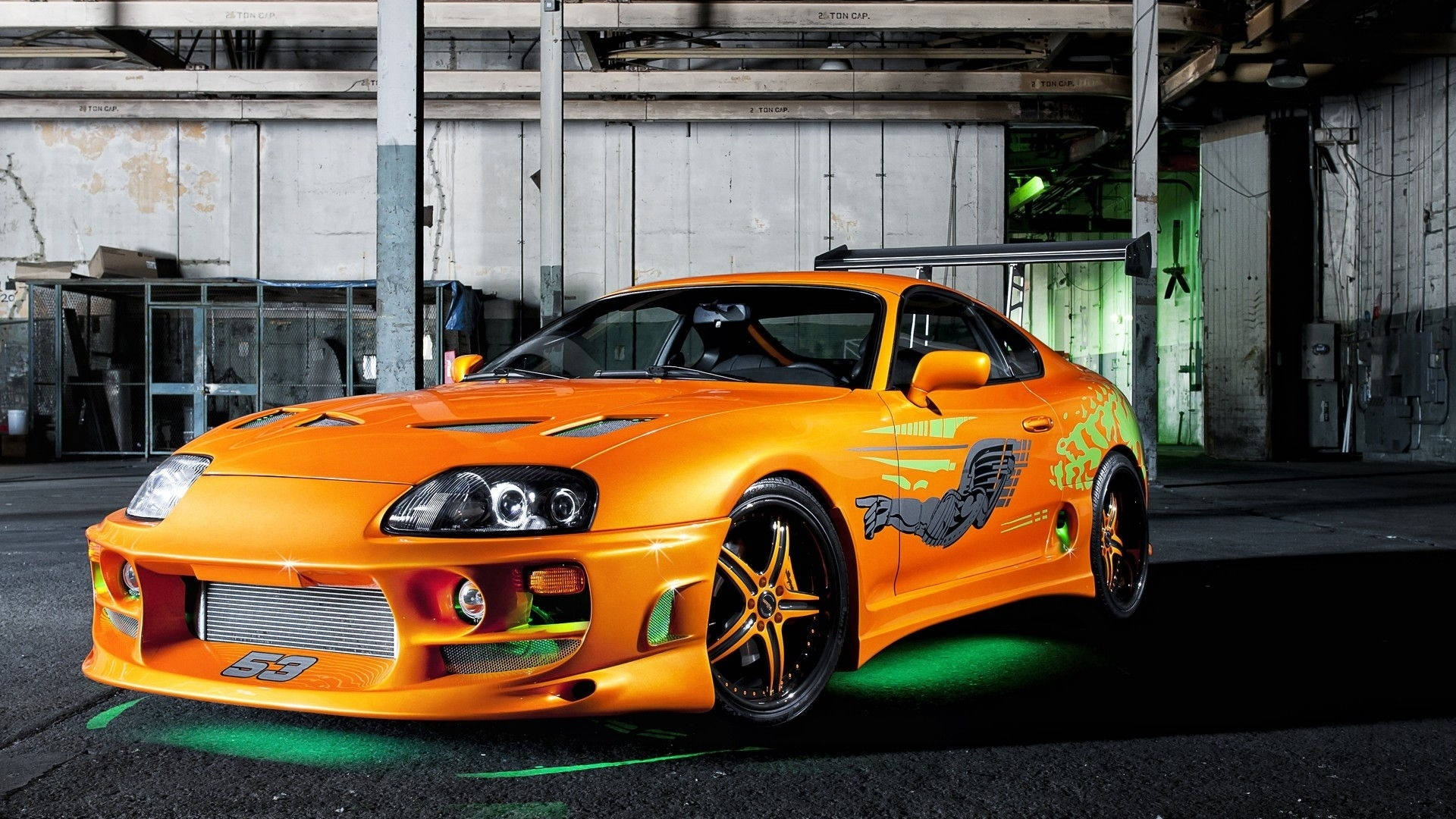 工業倉庫中帶綠色底盤燈的橙色改裝跑車。 — Toyota Supra Mk4 壁紙