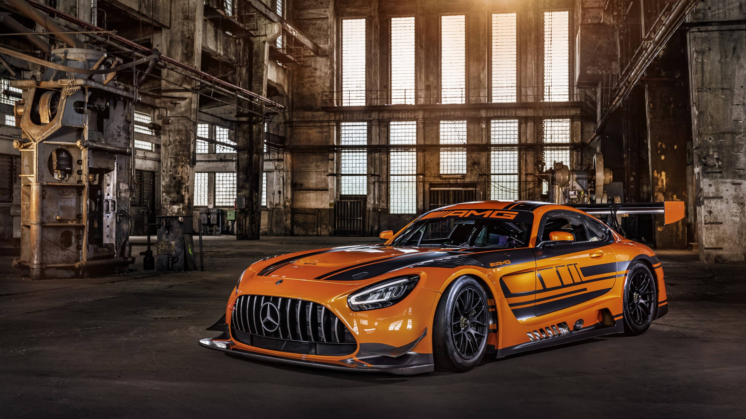 汽車 桌布 壁紙 — 一輛鮮橙色的 Mercedes-AMG GT3 賽車在破舊工廠倉庫的工業窗戶下閃閃發光。