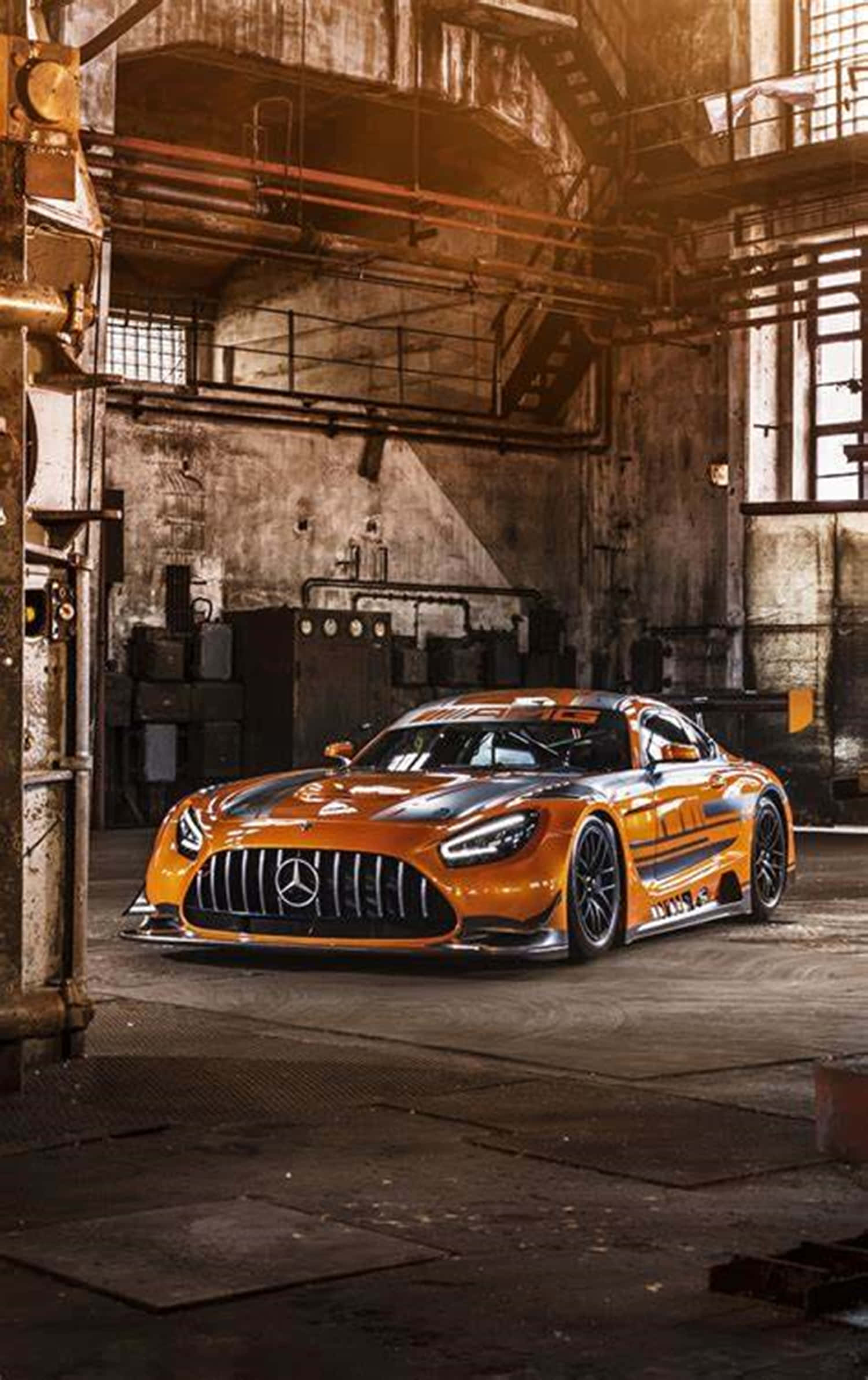 桌布 壁紙 — 一輛鮮橙色的 Mercedes-AMG GT3 賽車在破舊的工業倉庫內，於溫暖燈光下閃閃發光。