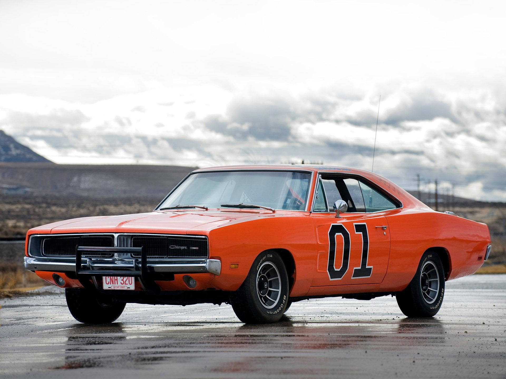 Charger 桌布 壁紙 — 一輛鮮橙色的1970年道奇Charger，帶有黑色賽車條紋和側面「01」，停泊在潮濕的道路上，天空多雲。