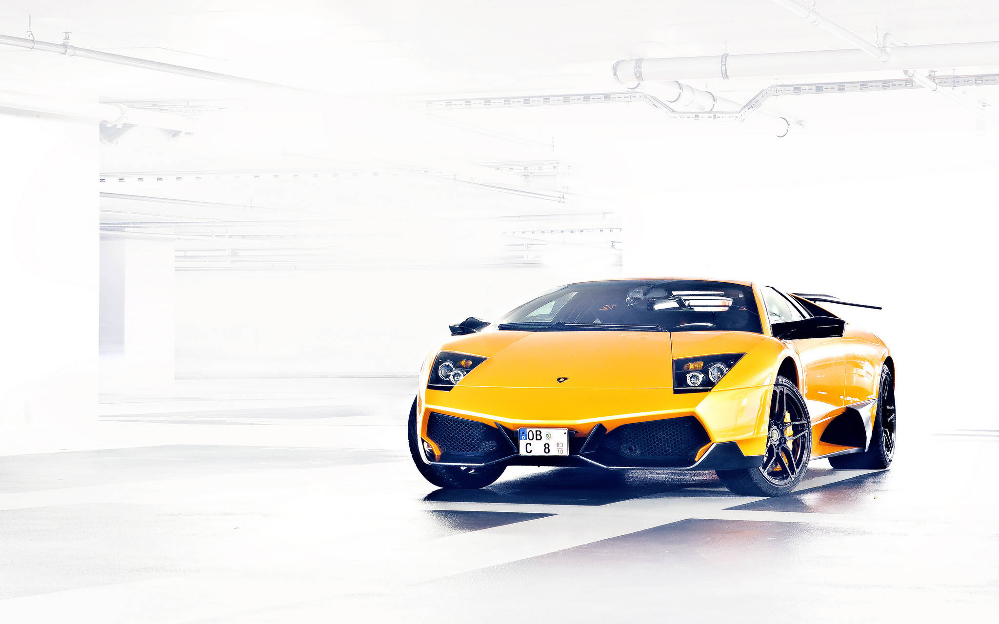 4K Lamborghini 桌布 壁紙 — 一輛鮮橙色的藍寶堅尼 Murciélago 停放在簡約白色地下車庫，配以戲劇性燈光。
