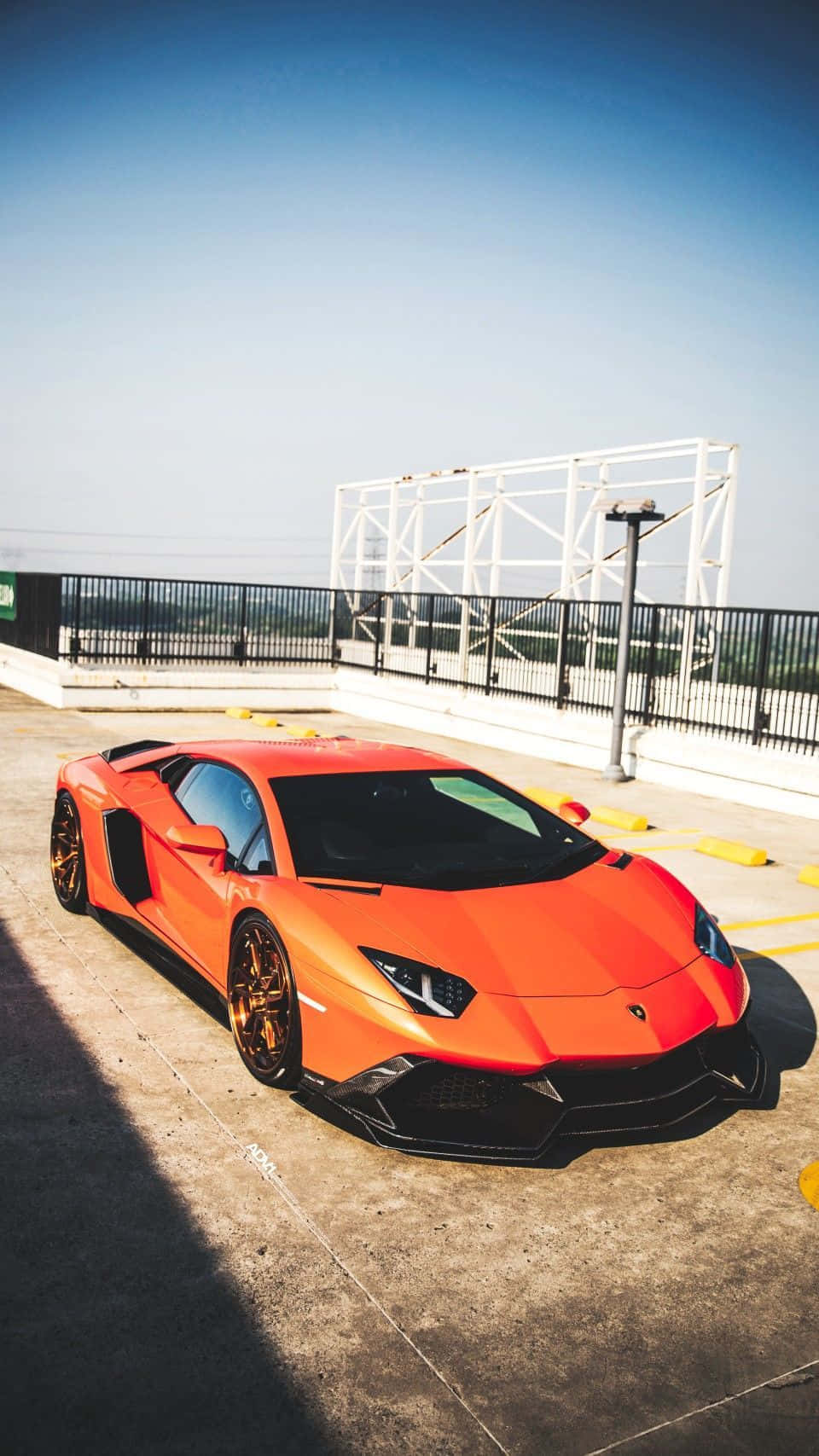 Pixel 3xl Lamborghini 桌布 壁紙 — 一輛鮮橙色藍寶堅尼Aventador停放在屋頂上，藍天白雲下帶有銳利陰影。