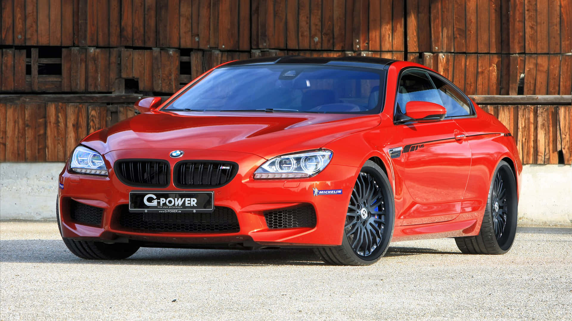 Bmw M6 桌布 壁紙 — 一輛鮮紅色G-Power改裝BMW M6雙門跑車停放在碎石上，前方是一道風化的木牆。
