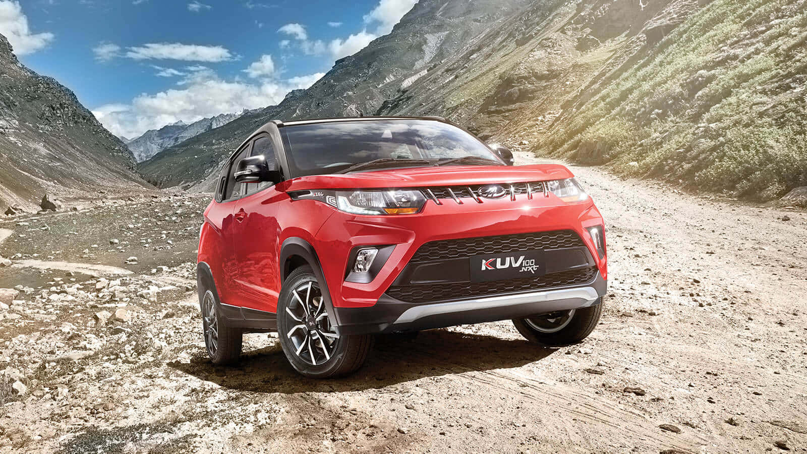 Mahindra 桌布 壁紙 — 一輛鮮紅色SUV停放在岩石山徑上，天空湛藍，白雲點綴。