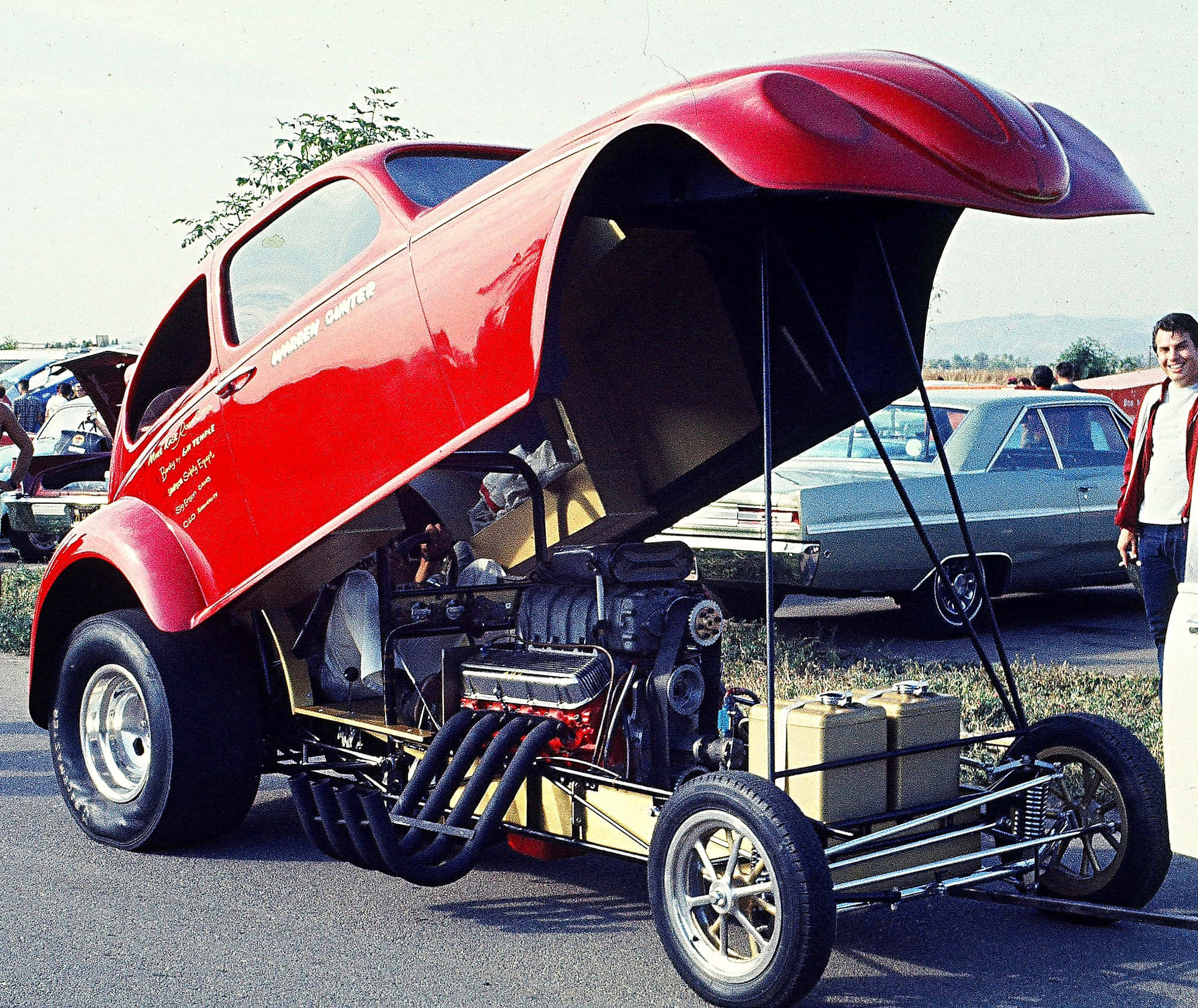 Funny Car 桌布 壁紙 — 一輛鮮紅色定制熱棒車掀起引擎蓋，在明亮的日光下於經典車展中展示強勁引擎。