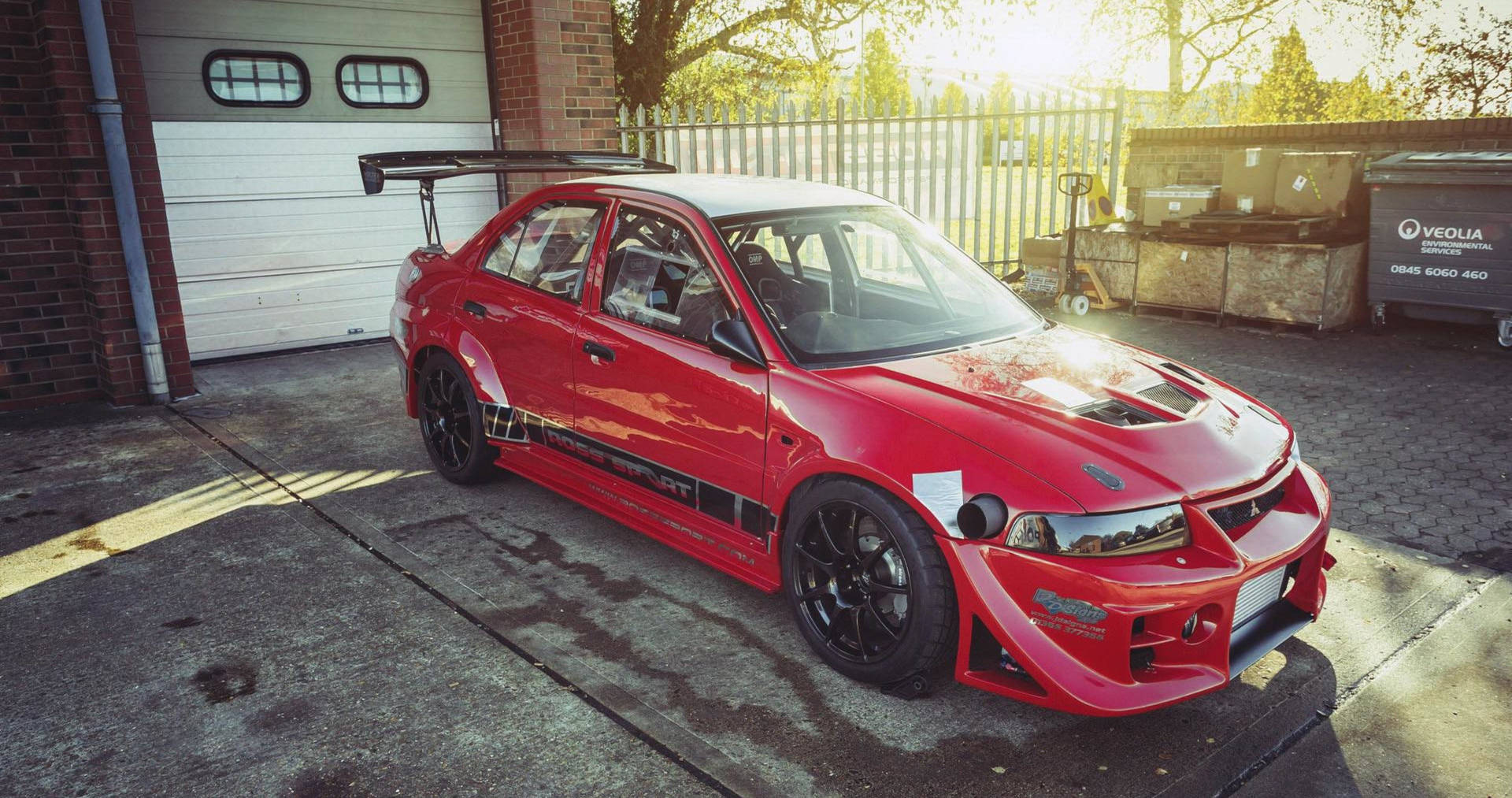 紅色改裝跑車停在磚砌車庫前，陽光投下長長的影子。 — 4K Jdm 壁紙
