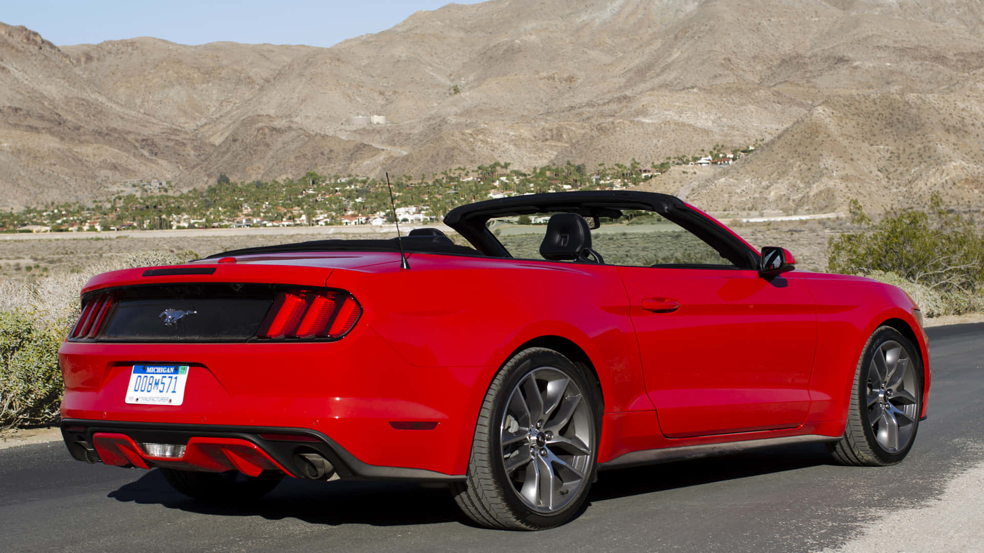 Ford Mustang Ecoboost 桌布 壁紙 — 一輛鮮紅色敞篷跑車停泊在沙漠公路上，背景是崎嶇的山脈。
