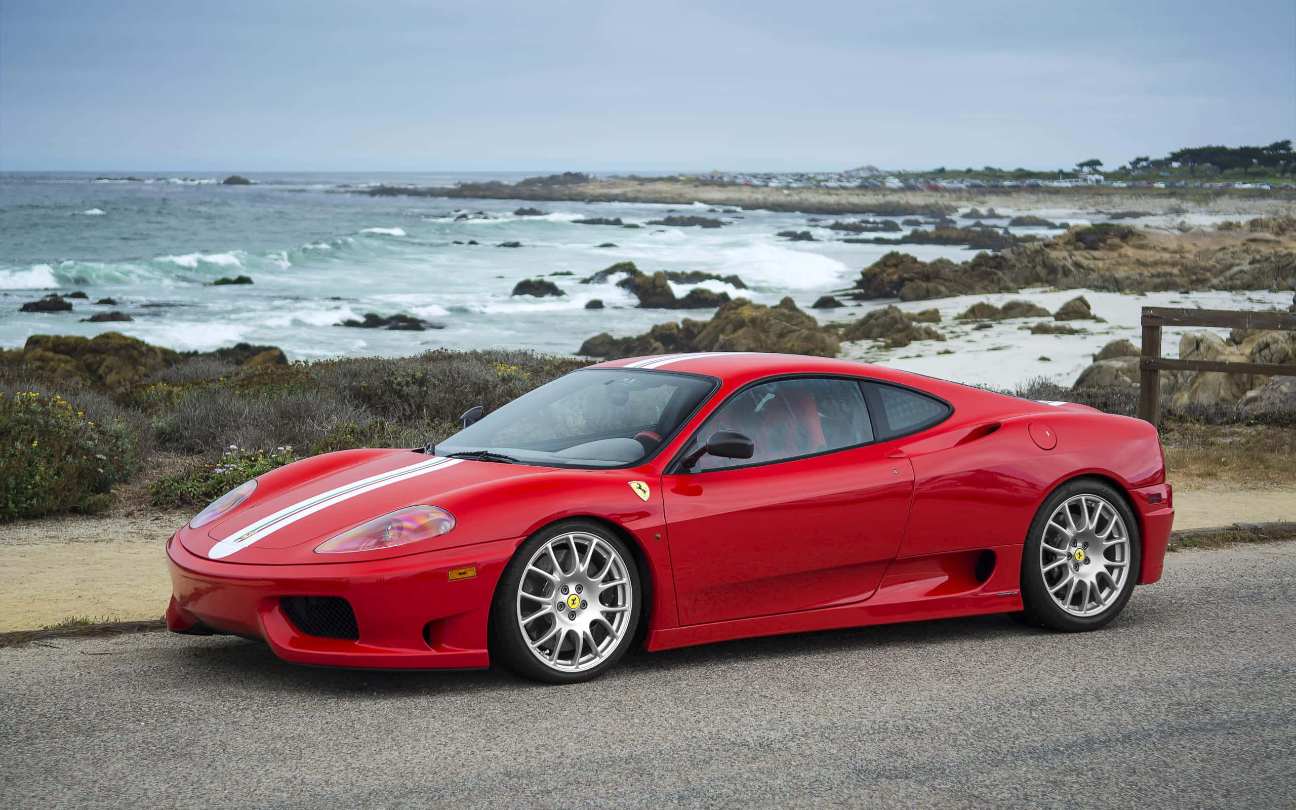 Ferrari 360 Modena 桌布 壁紙 — 一輛鮮紅色法拉利F430跑車停泊在海濱公路上，背景是翻騰的海浪和岩石海岸。