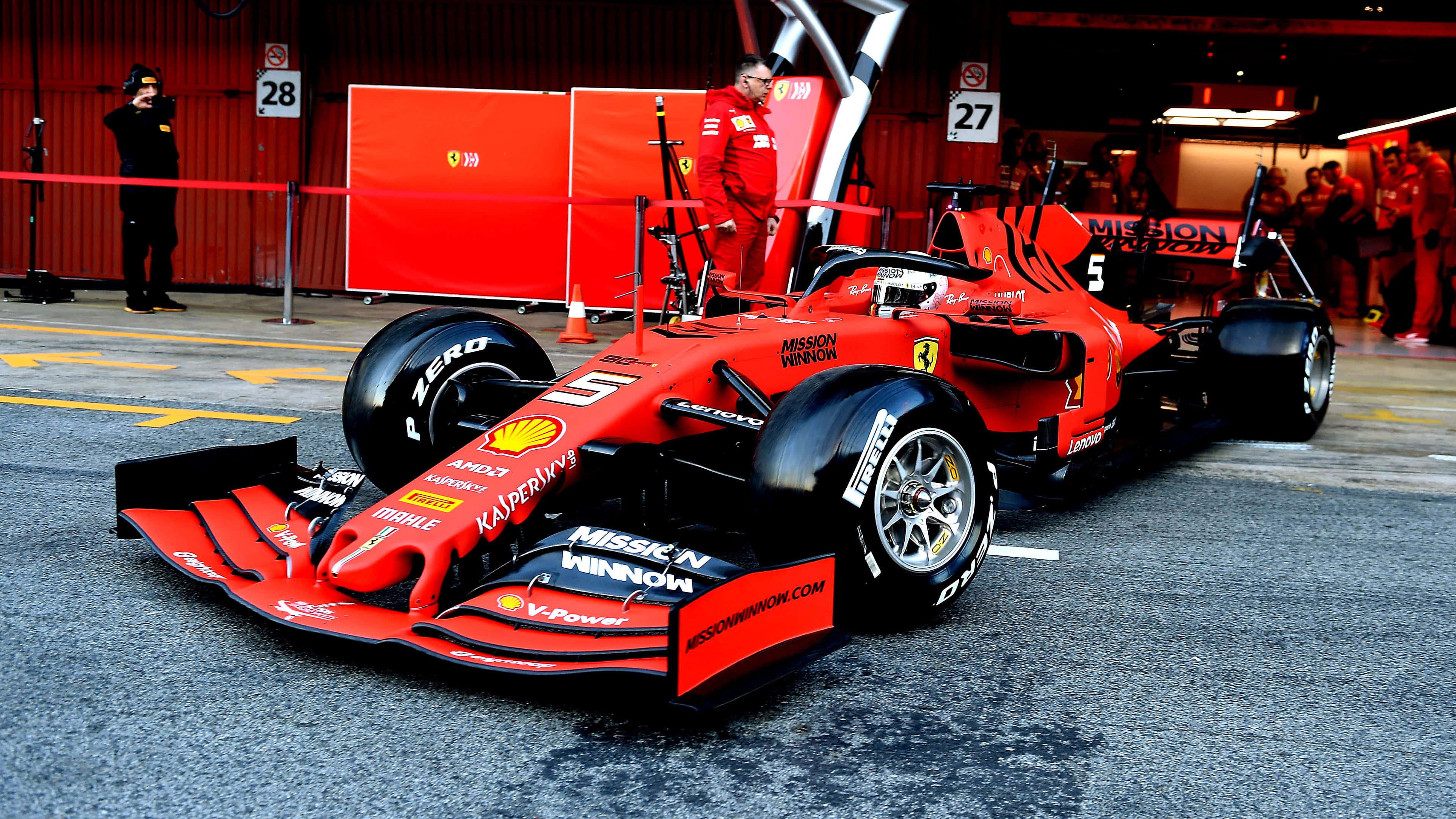 Racing 桌布 壁紙 — 一輛鮮紅色法拉利一級方程式賽車（編號5）停在維修站車庫，可見車隊成員和品牌標誌。