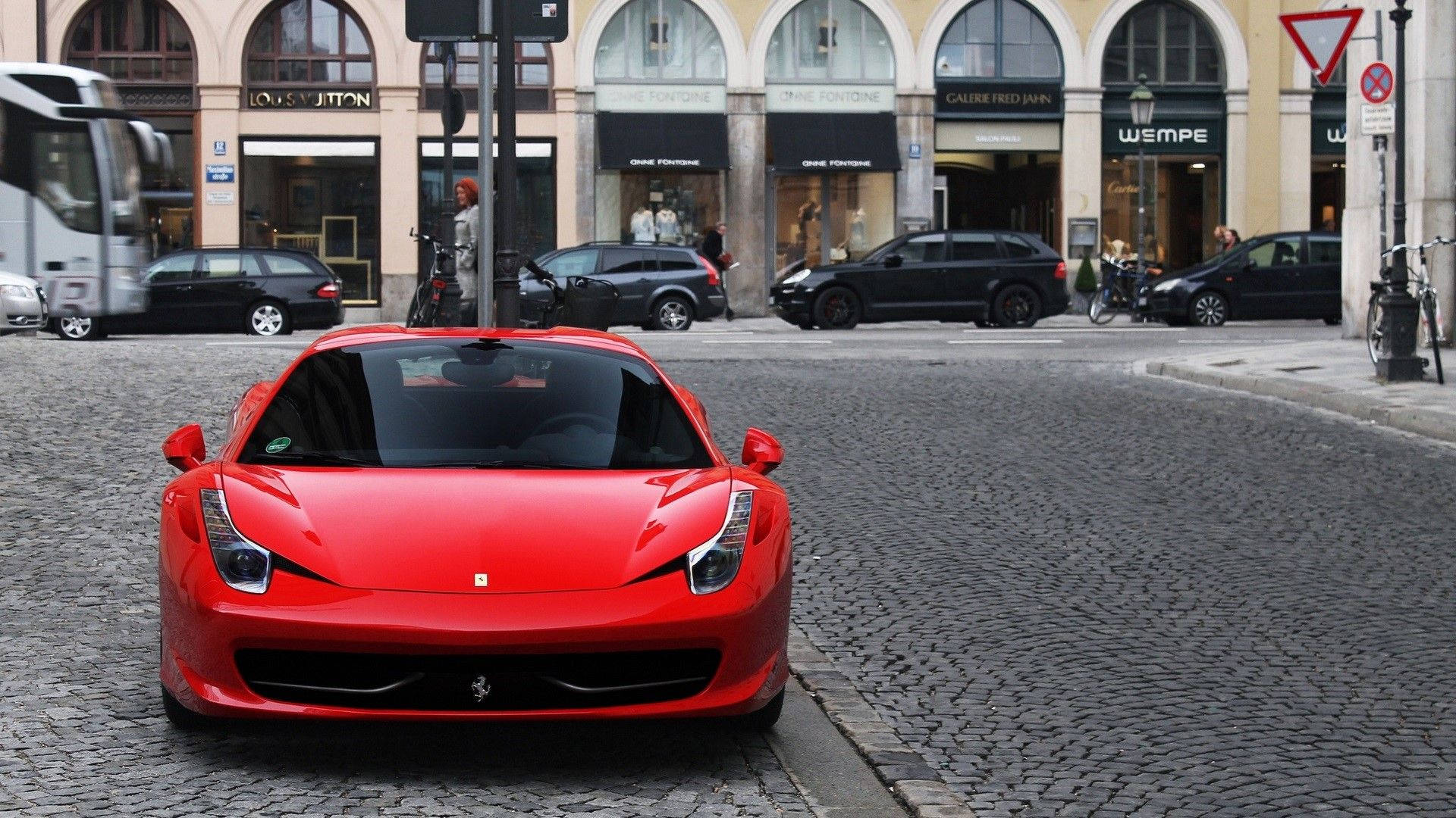 1920x1080 Ferrari 桌布 壁紙 — 一輛鮮紅色法拉利跑車停放在豪華精品店前的鵝卵石街道上。