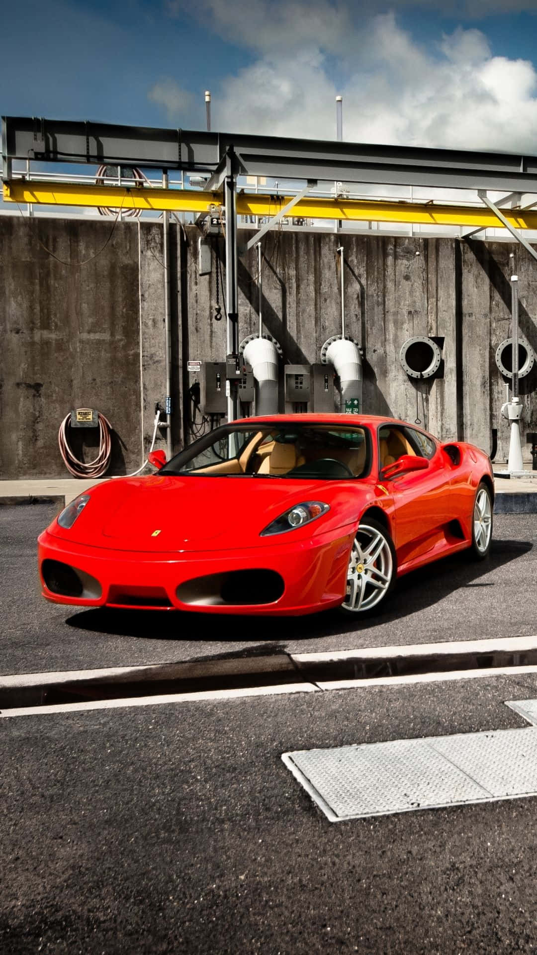 Ferrari F430 桌布 壁紙 — 一輛鮮紅色法拉利跑車停泊在瀝青路面上，前方是工業混凝土牆，天空部分多雲。