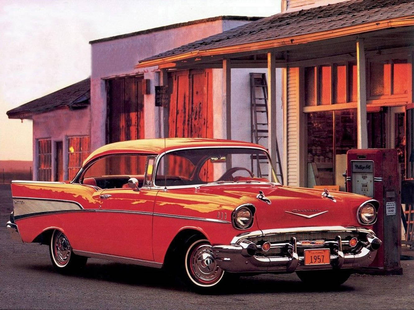 經典汽車 桌布 壁紙 — 一輛鮮紅色的1957年雪佛蘭Bel Air在溫暖的夕陽光下閃閃發光，停放在一間復古加油站。
