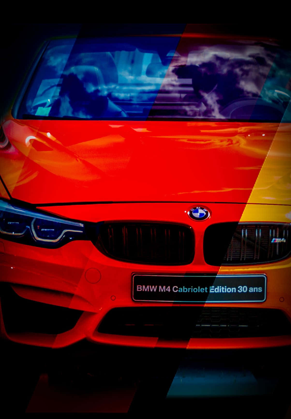 BMW 動圖 桌布 壁紙 — 一輛鮮紅色的BMW M4 Cabriolet Edition 30 ans在戲劇性的燈光下閃耀，引擎蓋和擋風玻璃上帶有彩色抽象覆蓋層。
