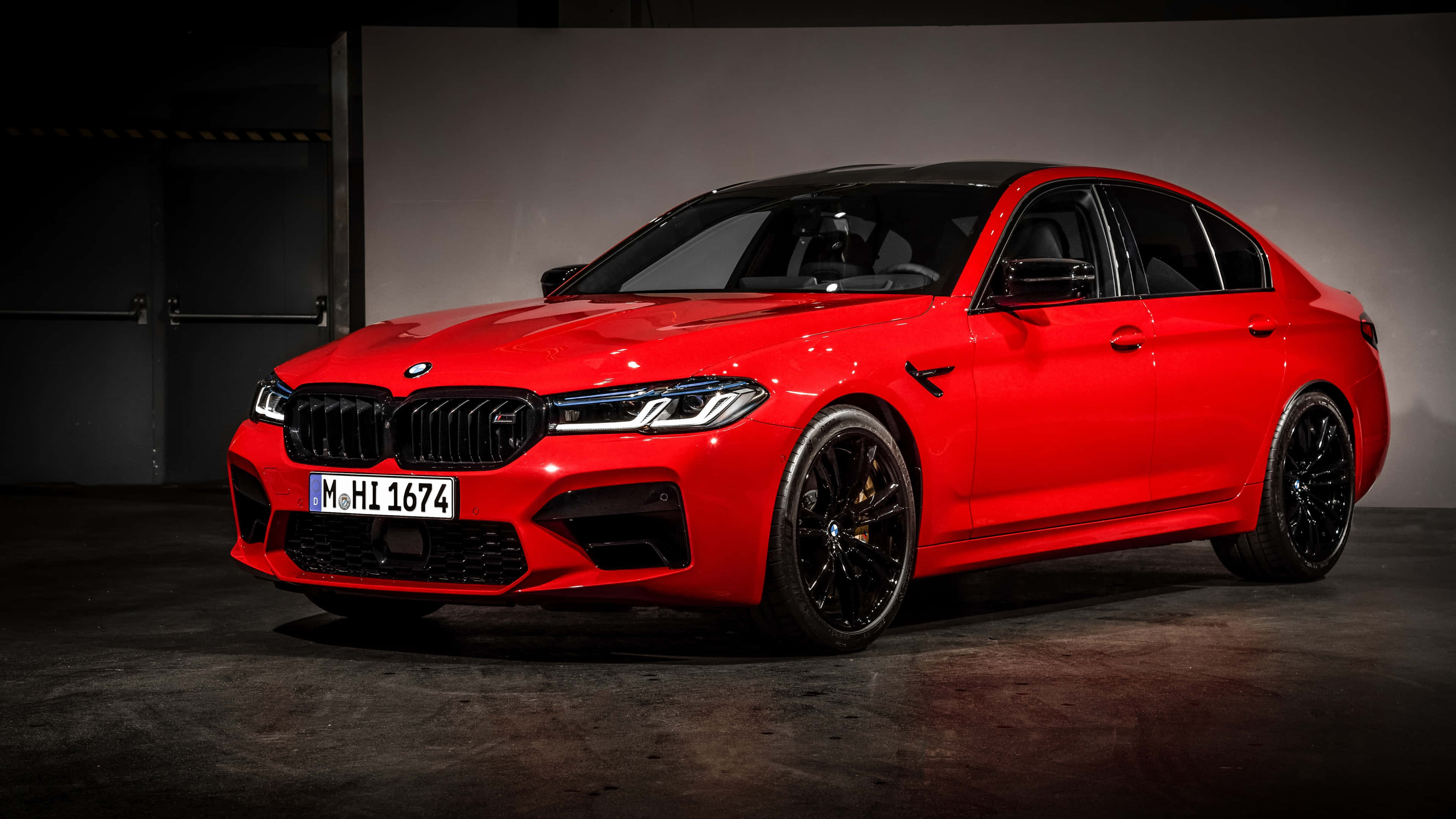 桌布 壁紙 — 一輛鮮紅色的BMW M5轎車在混凝土地面的黑暗工業車庫中，於攝影棚燈光下閃閃發光。