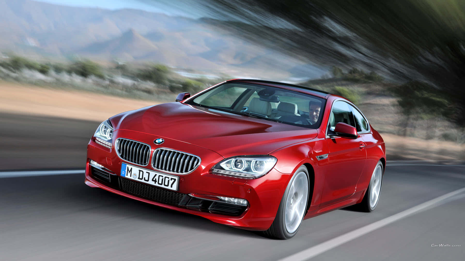 BMW 動圖 桌布 壁紙 — 一輛鮮紅色的BMW雙門跑車在蜿蜒的道路上行駛，背景是模糊的山巒。