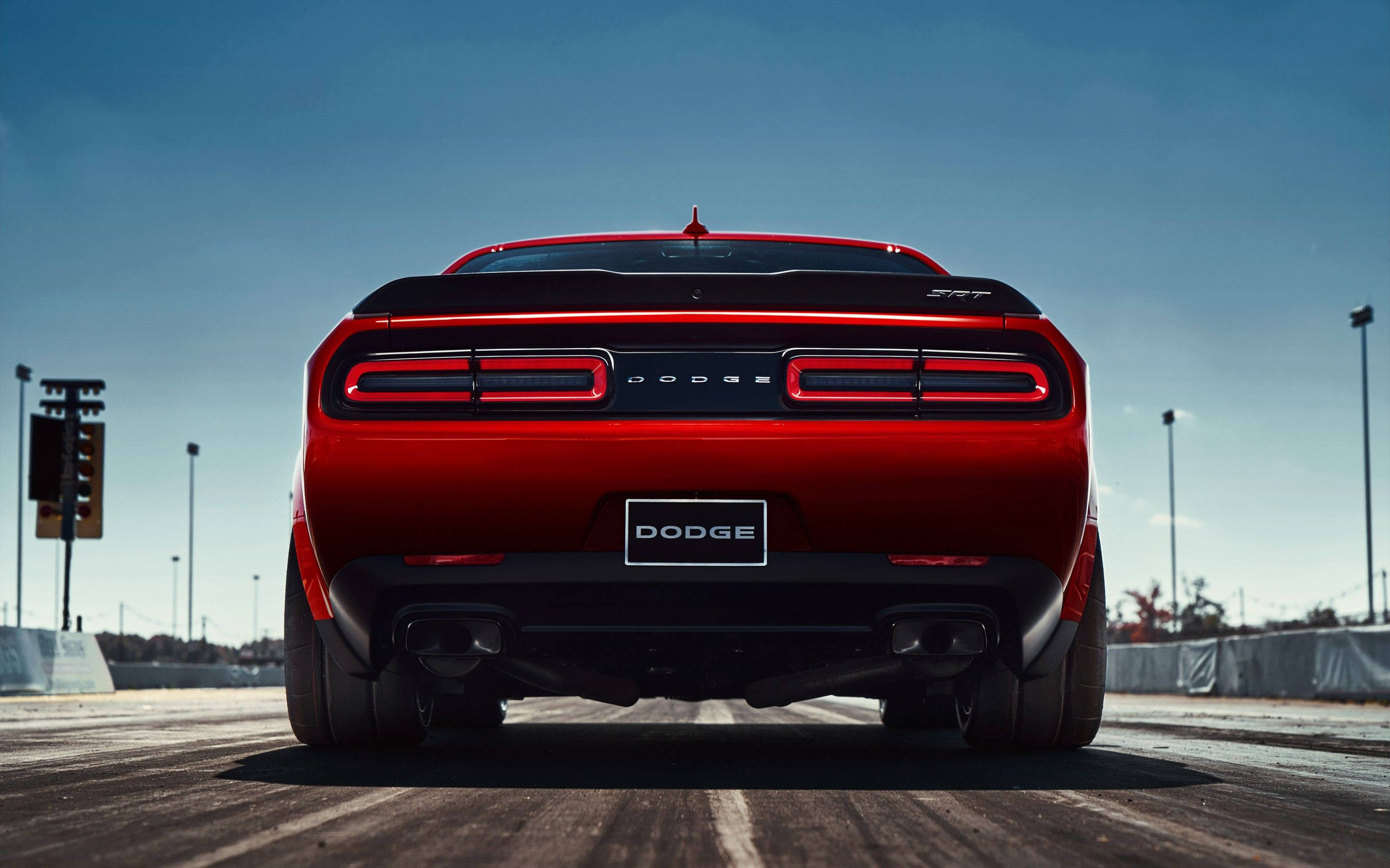 Dodge 桌布 壁紙 — 一輛鮮紅色的Dodge Challenger SRT在晴朗藍天下的賽道上展現其後方視角。