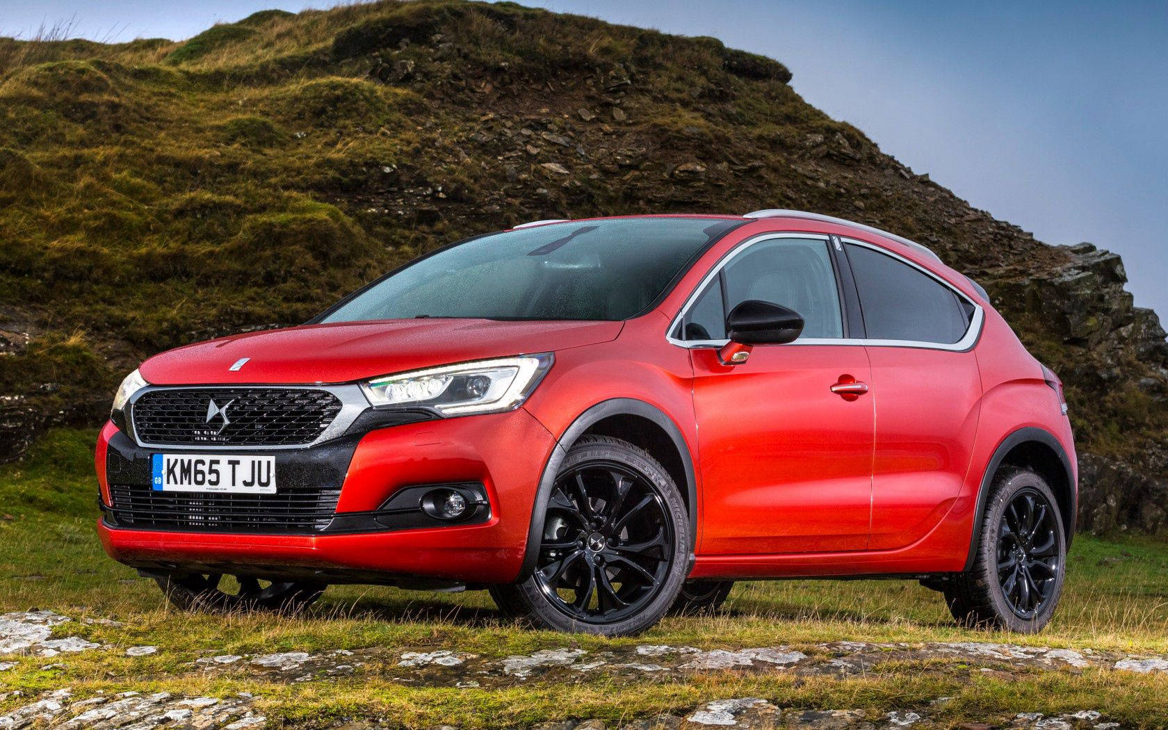 Citroen 桌布 壁紙 — 一輛鮮紅色的DS 4 Crossback SUV停泊在草地地形上，背景有長滿苔蘚的山丘和清澈的藍天。