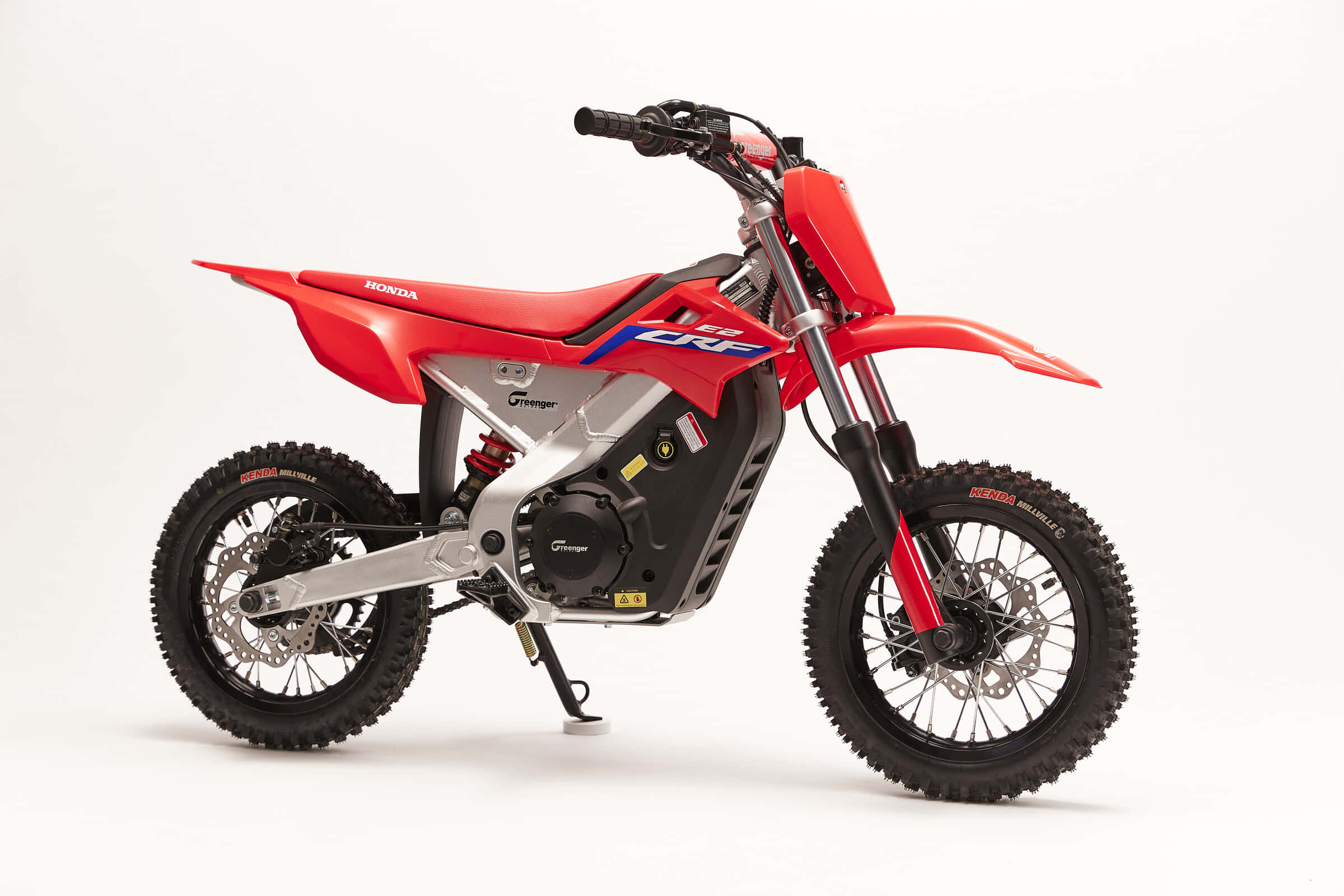 Dirtbike 桌布 壁紙 — 一輛鮮紅色的Honda CRF電動越野摩托車矗立在潔白的工作室地板上，展示其堅固的輪胎和流線型現代設計。