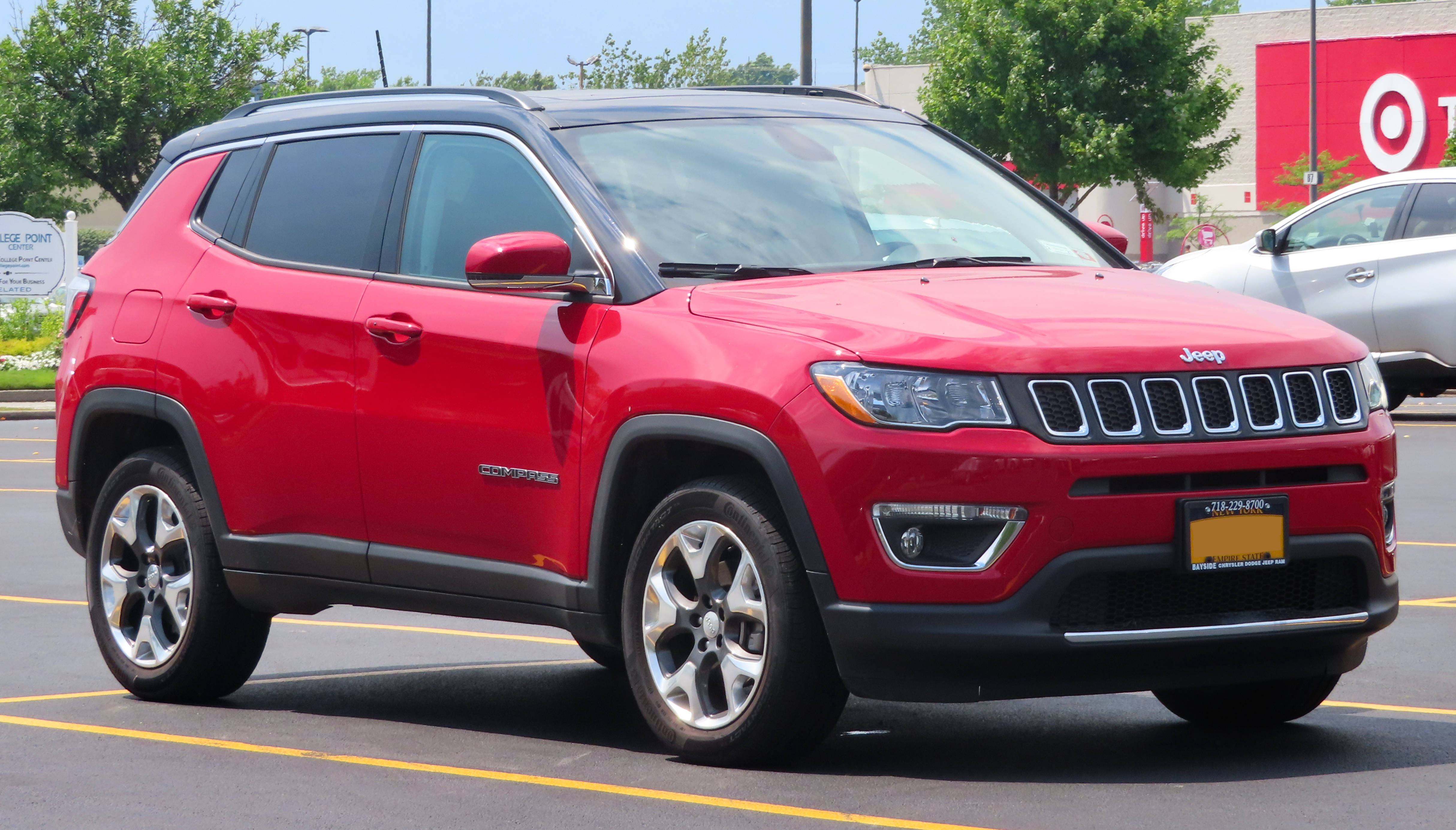 driving 桌布 壁紙 — 一輛鮮紅色的Jeep Compass SUV停放在陽光明媚的停車場，背景有樹木和Target商店。