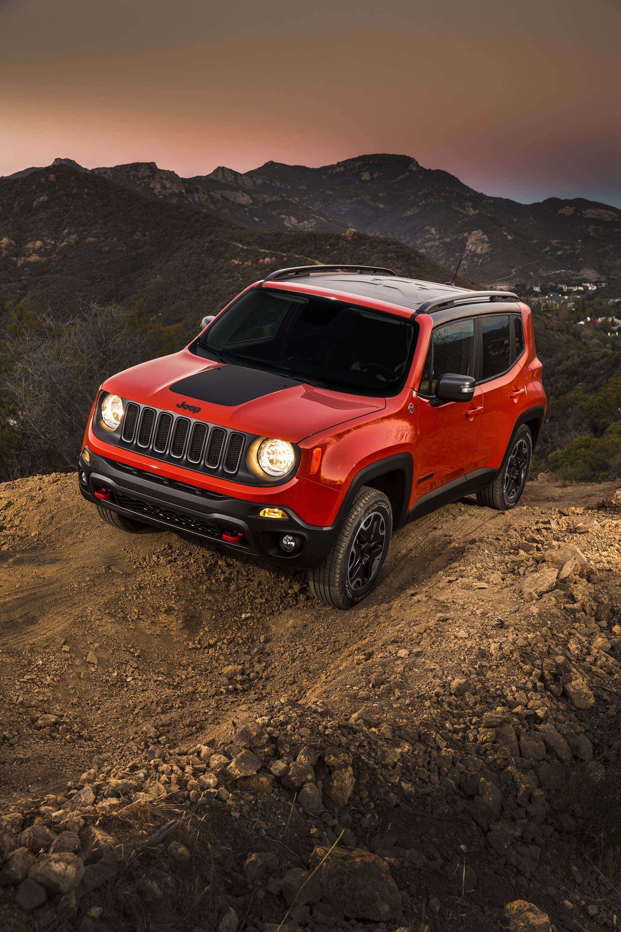 Jeep Renegade 桌布 壁紙 — 一輛鮮紅色的Jeep Renegade在日落時分於山脈頂端的崎嶇泥路上行駛。