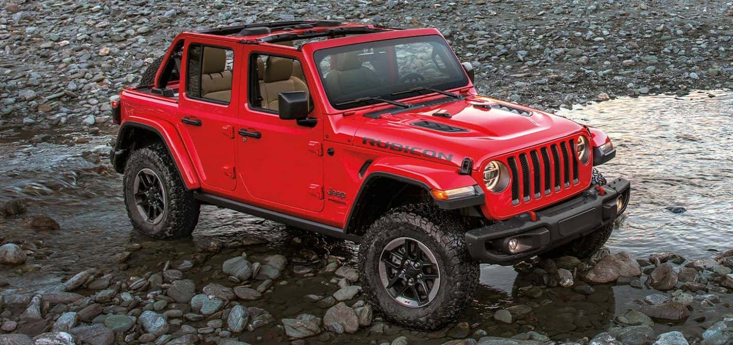 吉普 桌布 壁紙 — 一輛鮮紅色的Jeep Wrangler Rubicon在淺石溪中行駛，堅固的輪胎濺起水花。
