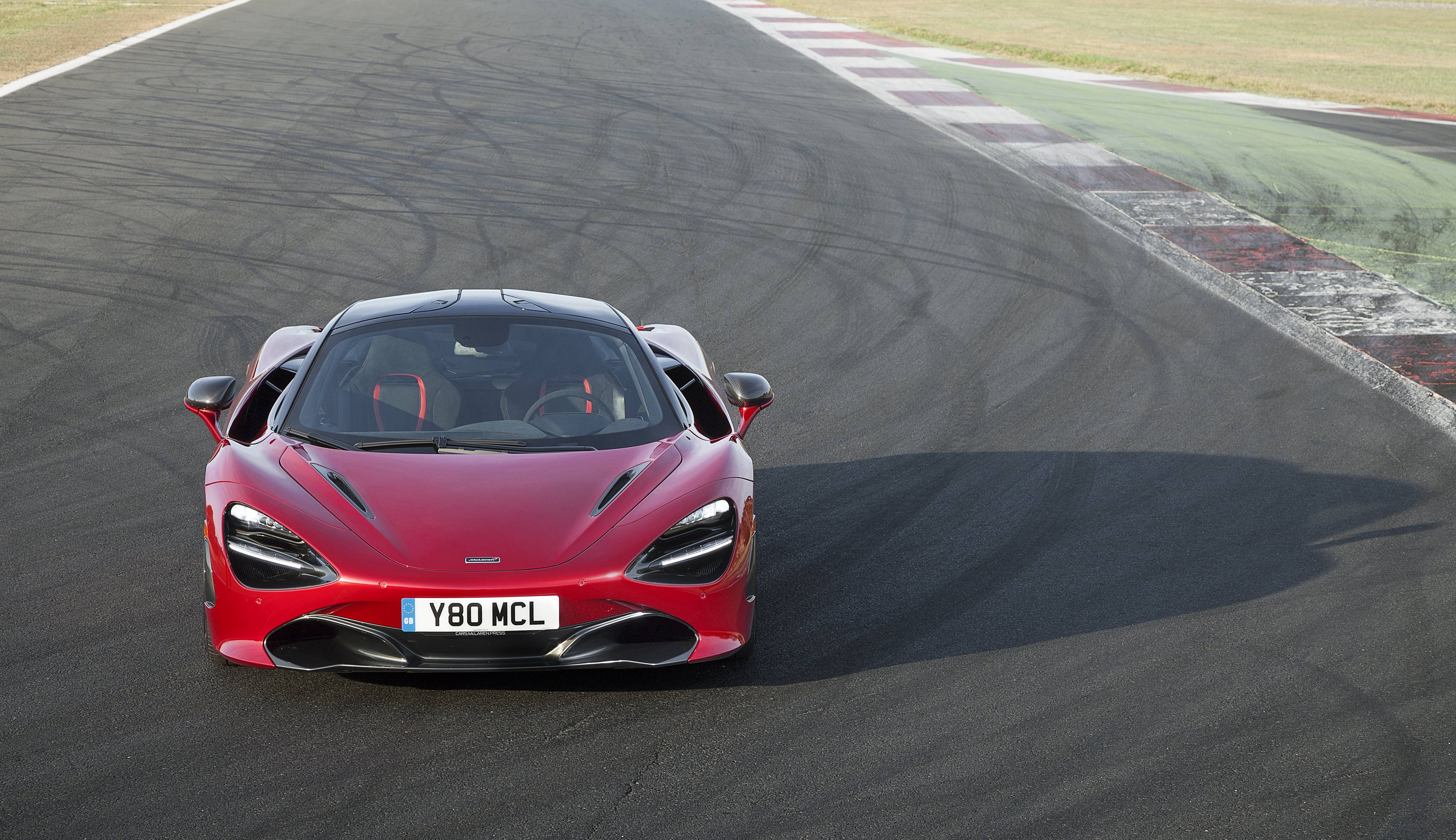 mclaren 720s 4K 桌布 壁紙 — 一輛鮮紅色的McLaren 720S跑車在明亮的日光下沿著賽道奔馳，輪胎痕跡和路緣清晰可見。