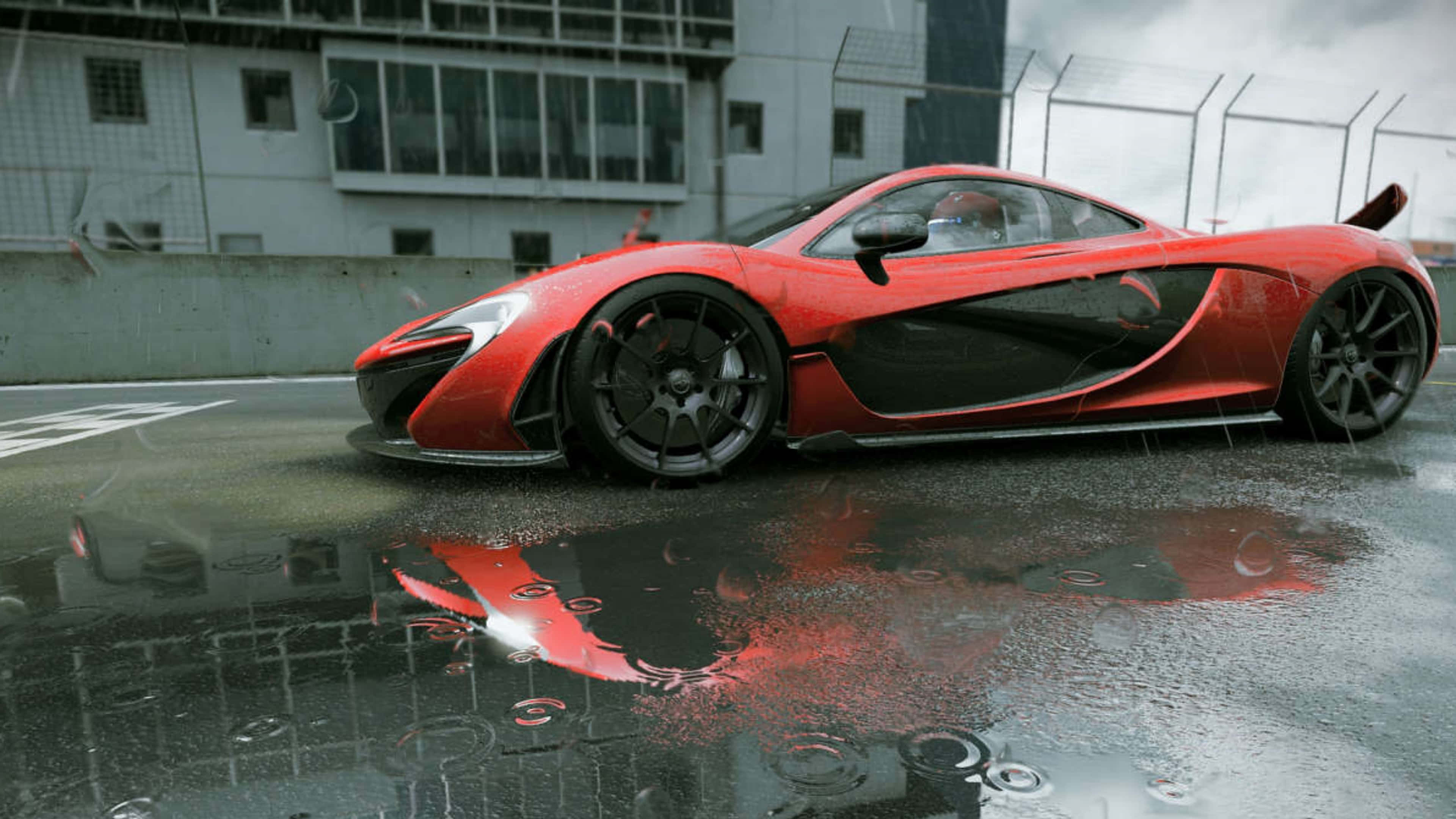 Mclaren P1 桌布 壁紙 — 一輛鮮紅色的McLaren跑車在潮濕的賽道上閃閃發光，雨滴在水坑中泛起漣漪，映照出其流線型車身。