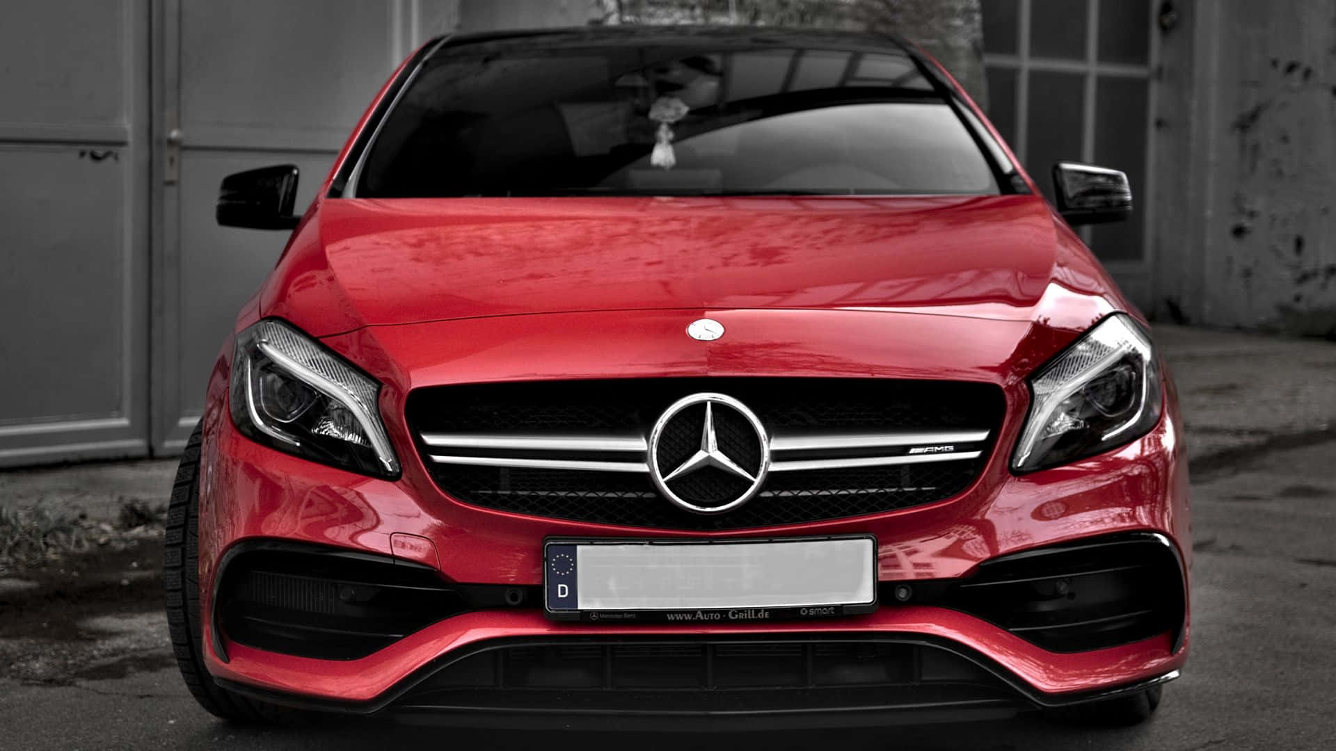 主題 桌布 壁紙 — 一輛鮮紅色的Mercedes-AMG A45 S跑車在日光下閃耀，背景是單色工業場景。