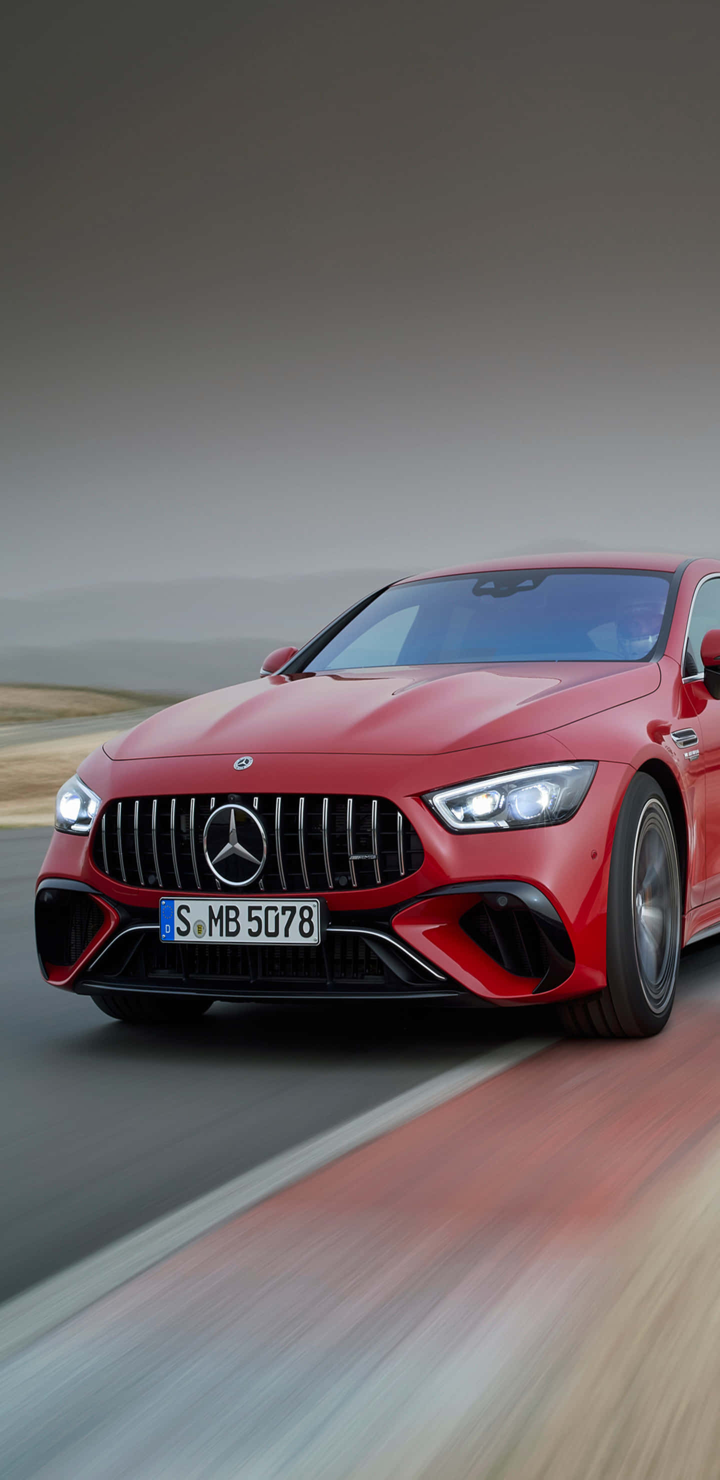 Car Images HD 桌布 壁紙 — 一輛鮮紅色的Mercedes-AMG GT R在朦朧的天空下，沿著模糊的沙漠道路飛馳。
