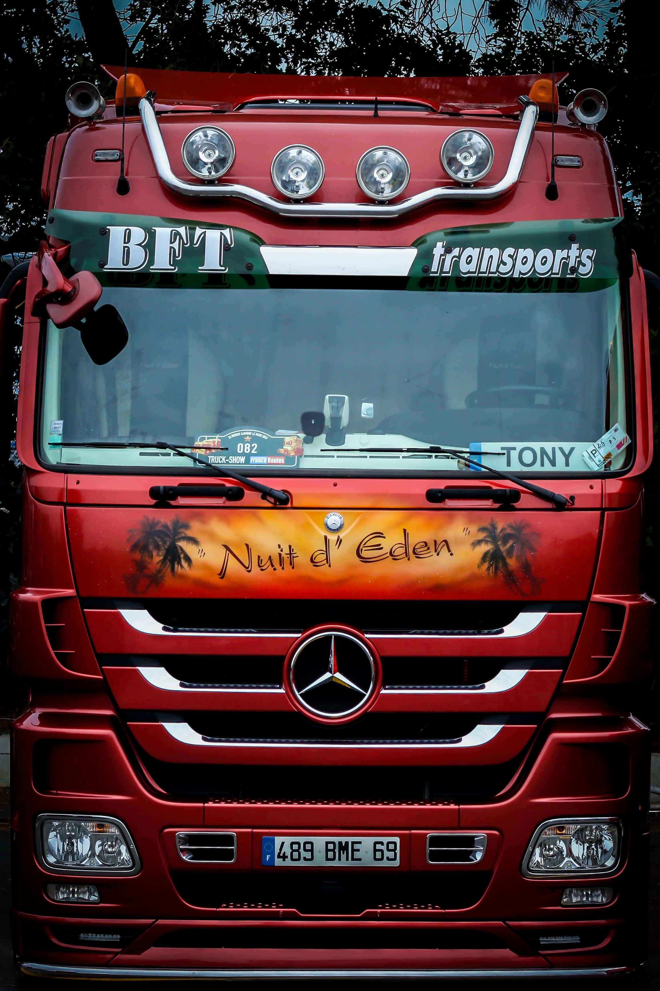 桌布 壁紙 — 一輛鮮紅色的Mercedes-Benz卡車，前格柵上有「Nuit d'Eden」棕櫚樹藝術品和「BFT transports」品牌標誌。