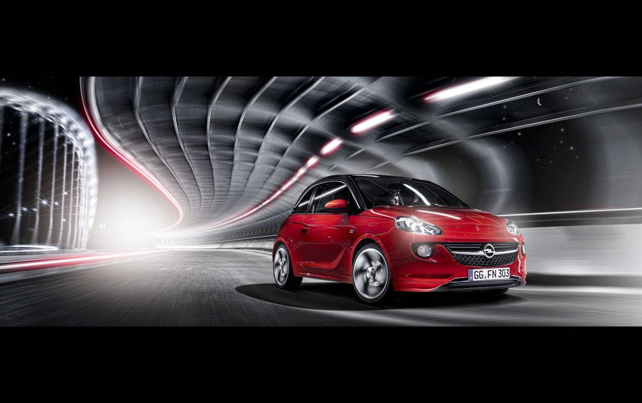 Opel 桌布 壁紙 — 一輛鮮紅色的Opel Adam在未來主義隧道中疾馳，隧道內有發光的條紋和彎曲的金屬牆壁。