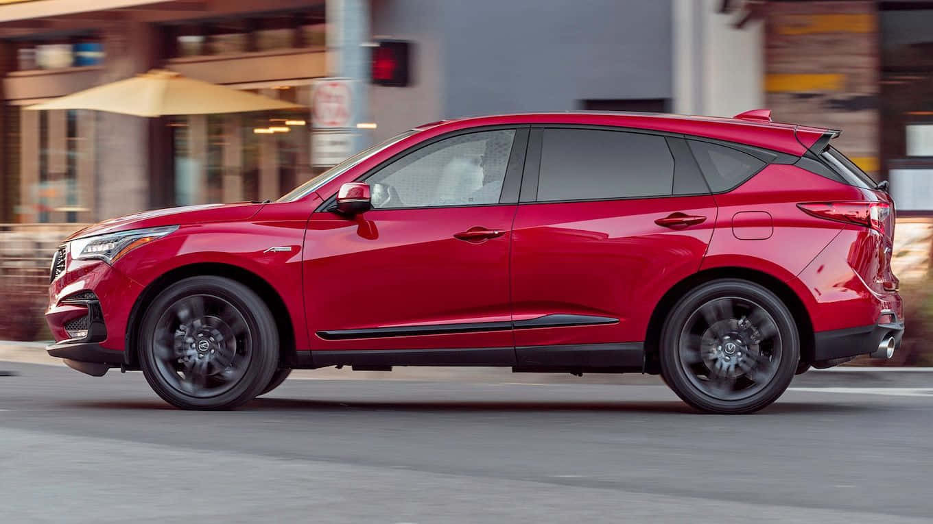 Acura Rdx 桌布 壁紙 — 一輛鮮紅色的SUV在城市街道上行駛，背景模糊，車輪帶有動態模糊效果。