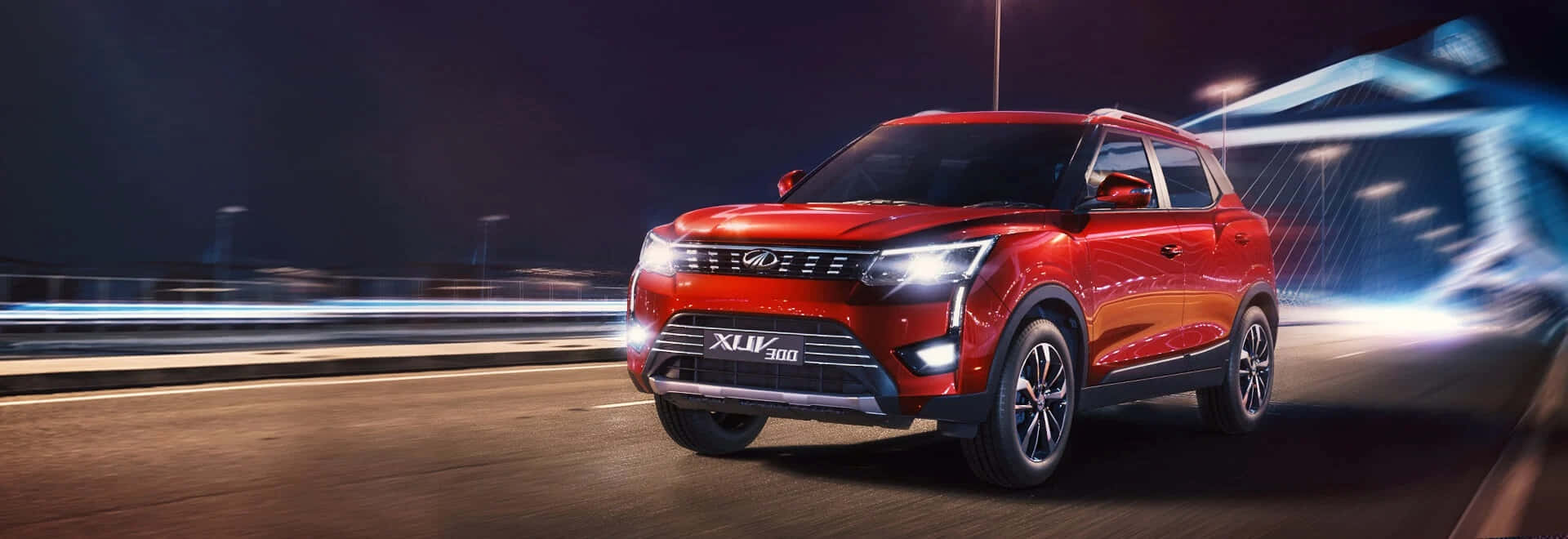 Mahindra 桌布 壁紙 — 一輛鮮紅色的SUV在夜間高速公路上疾馳，車頭燈閃爍，城市燈光因動態模糊而劃過。