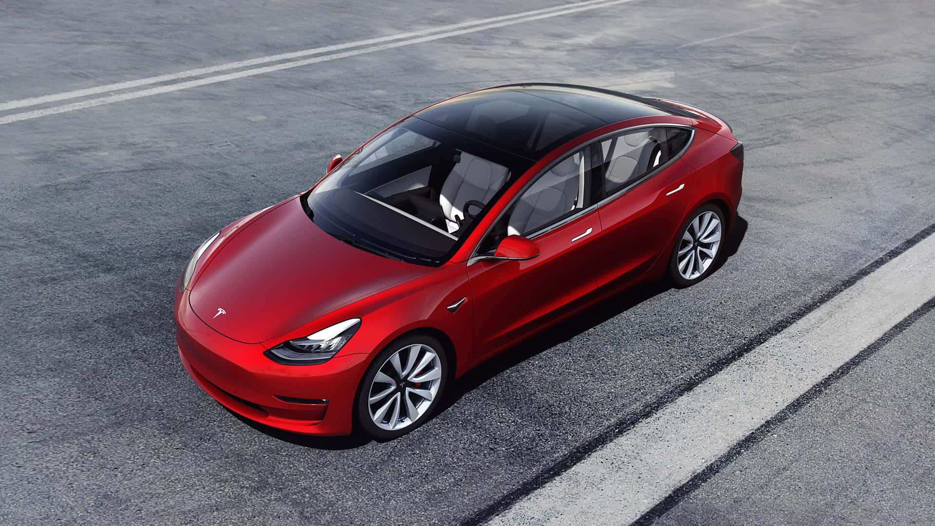Tesla Model 3 桌布 壁紙 — 一輛鮮紅色的Tesla Model 3停放在灰色瀝青停車場上，在明亮的日光下。