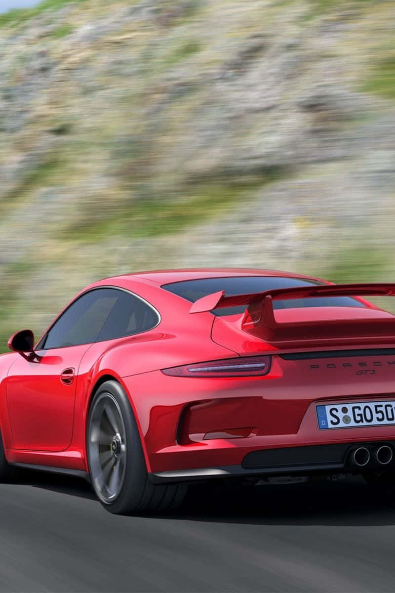 911 iPhone 桌布 壁紙 — 一輛鮮紅色的保時捷911 GT3沿著蜿蜒的山路疾馳，模糊的綠色景物呼嘯而過。