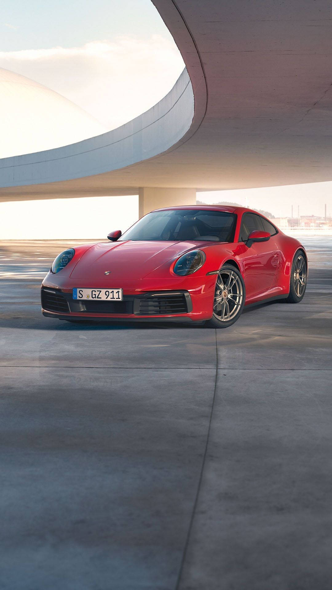 Porsche 911 桌布 壁紙 — 一輛鮮紅色的保時捷911雙門跑車停放在現代弧形混凝土結構下，光線柔和。